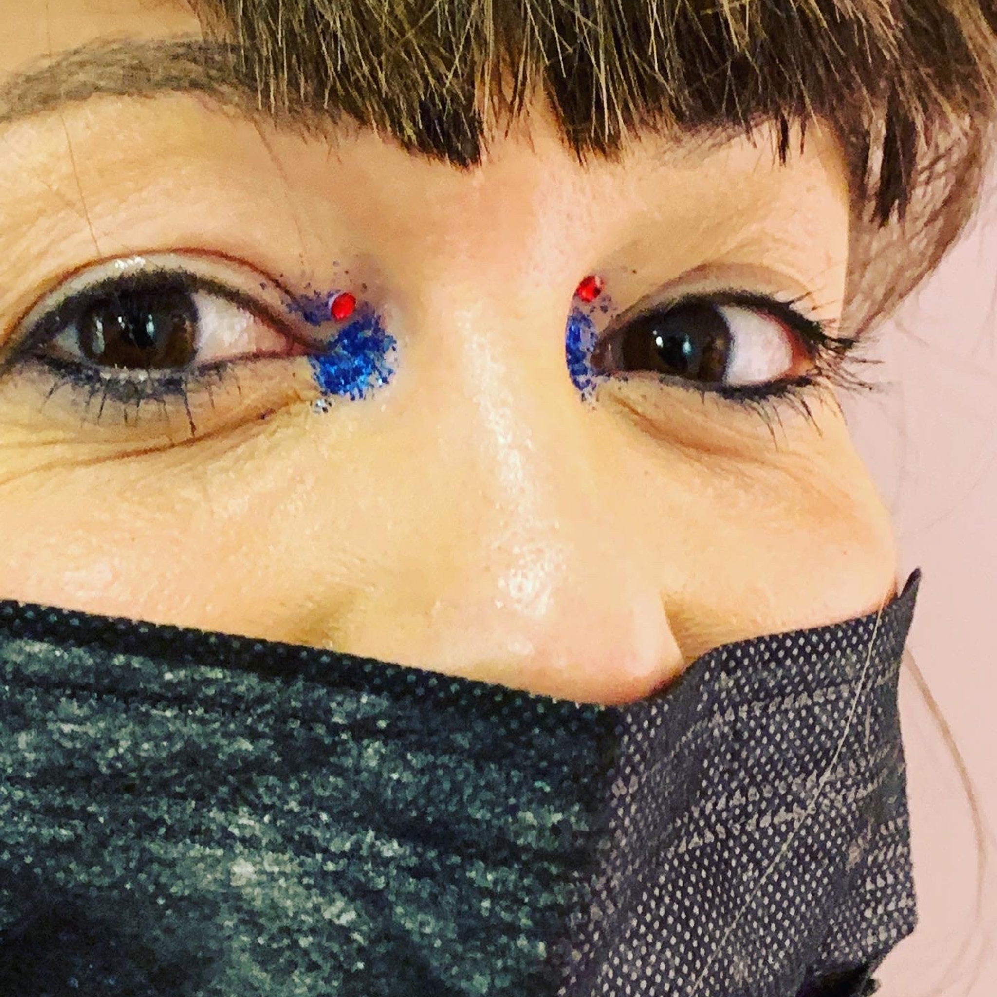 Mask with black and white dotted pattern, covering mouth and nose, with eye makeup visible