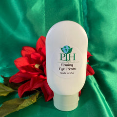 Firming eye cream in white bottle with green cap, red flower on green fabric background