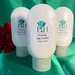 Firming eye cream in white plastic bottles with PIH label and green cap on green fabric
