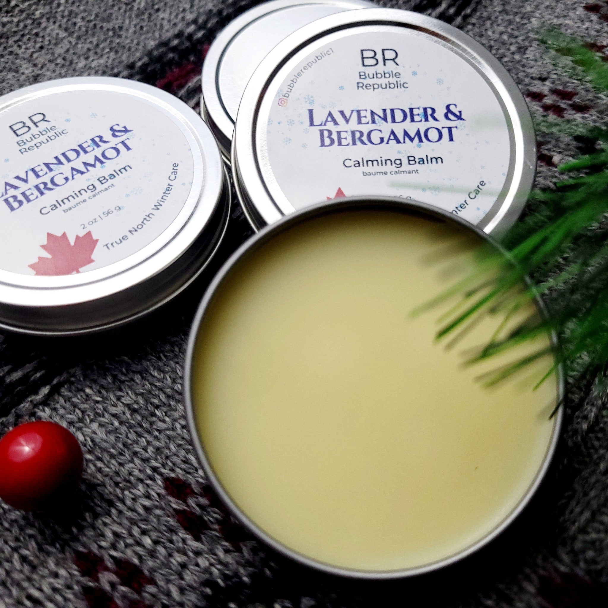 Calming balm in silver tin, pale yellow balm, and gray knit background with BR brand label visible