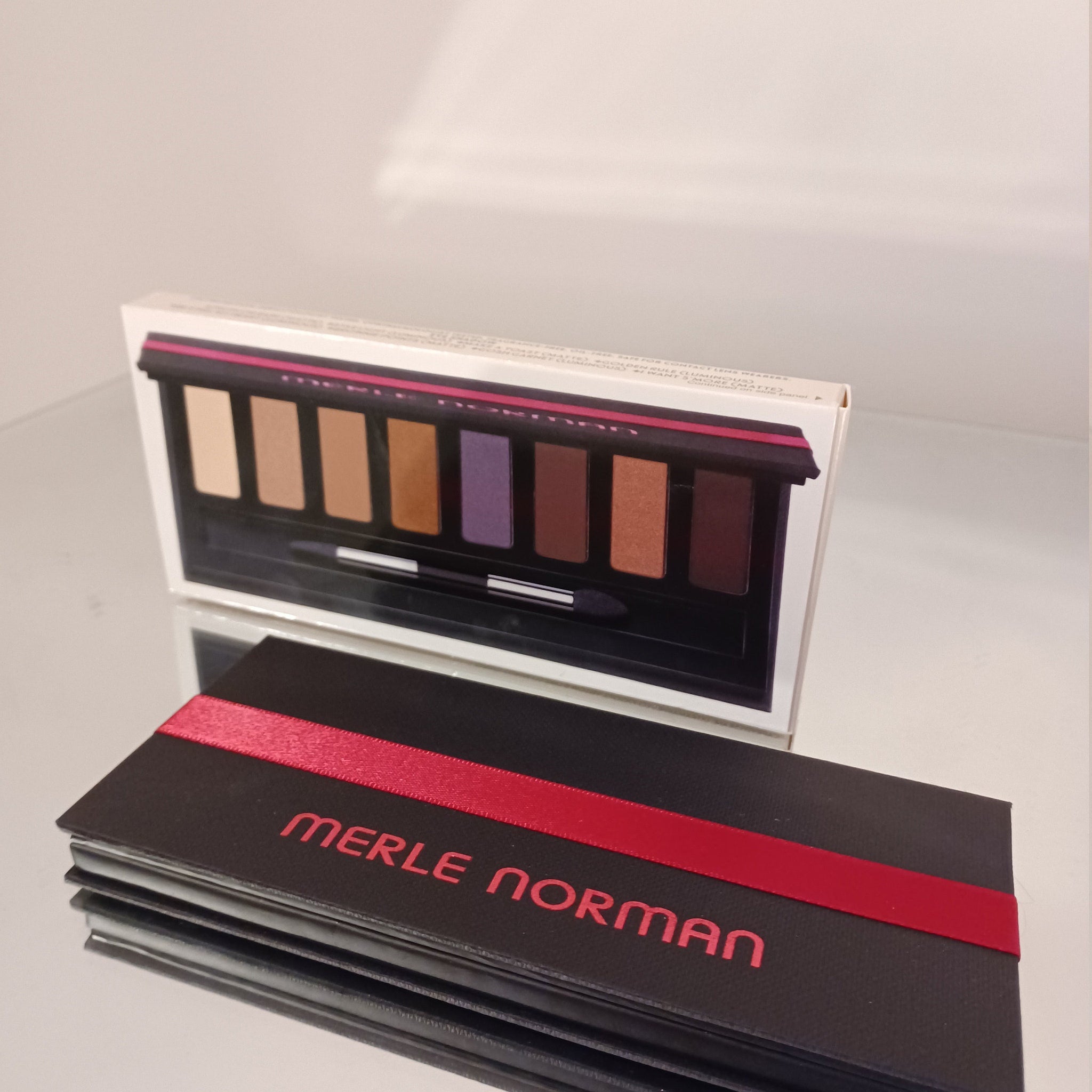 Open compact showing six shimmering eyeshadows in bronze, gold, and pink tones with two blush pans
