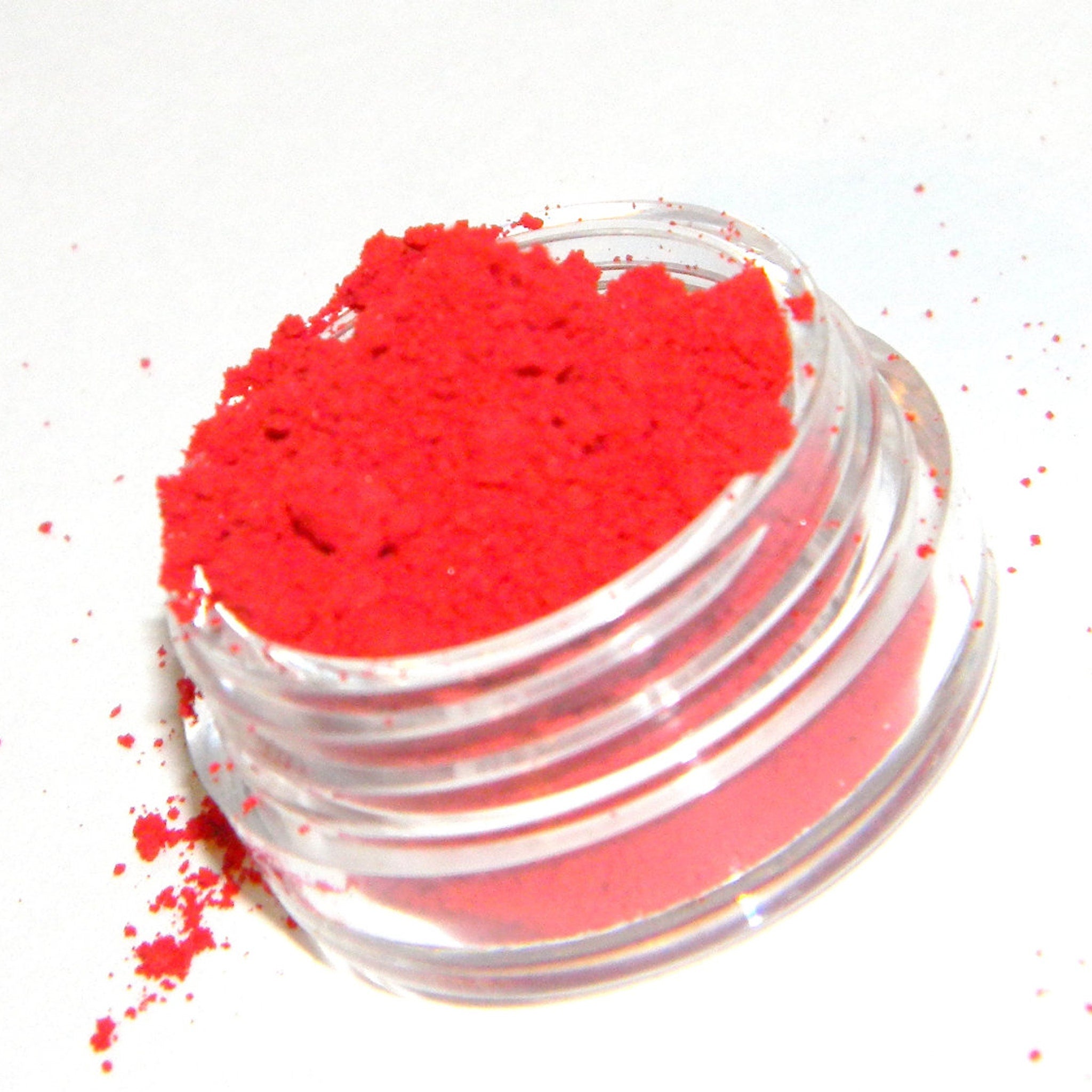 Close-up of matte red eye shadow pan with smooth, velvety texture in a sleek black compact.