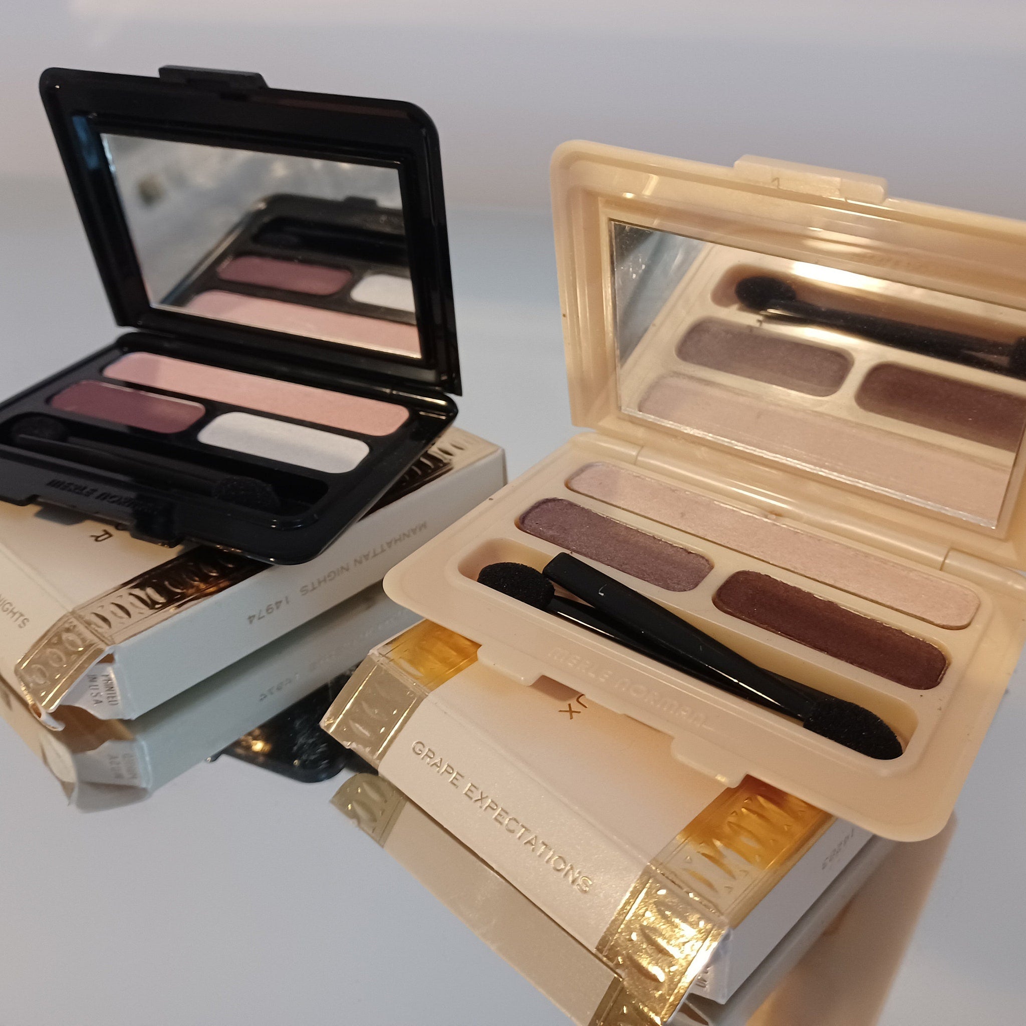 Eyeshadow palettes with black and beige cases, various shades of eyeshadow, and applicators