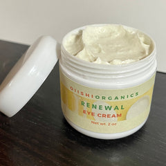 Eye cream in white jar with cream, label, and lid on dark surface