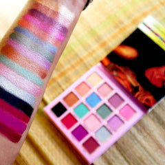Hand applying shimmery bronze eyeshadow from palette to eyelid with blending brush