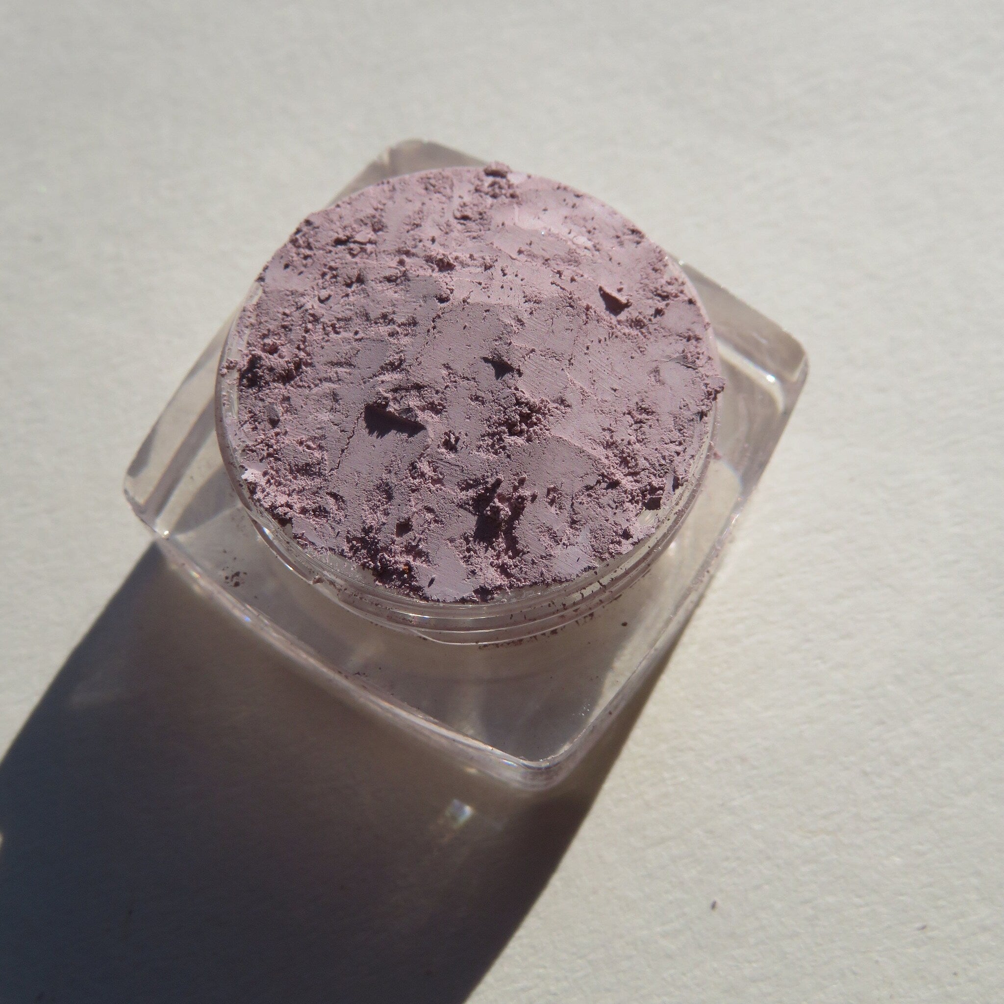 Close-up of loose matte eyeshadow powder in soft pale purple hue with mineral texture