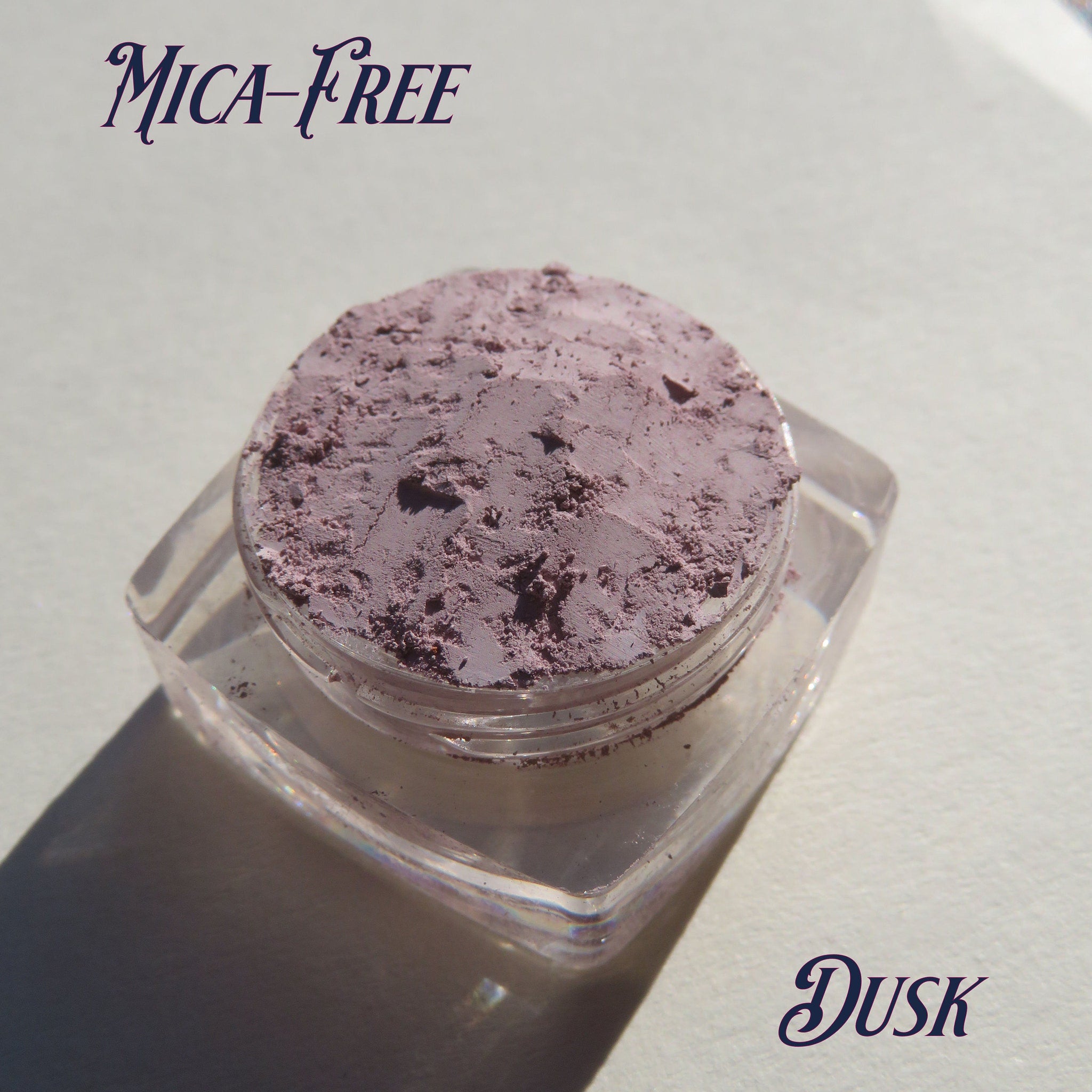 Side view of loose mineral eyeshadow in muted pale purple matte finish, showcasing fine powder texture