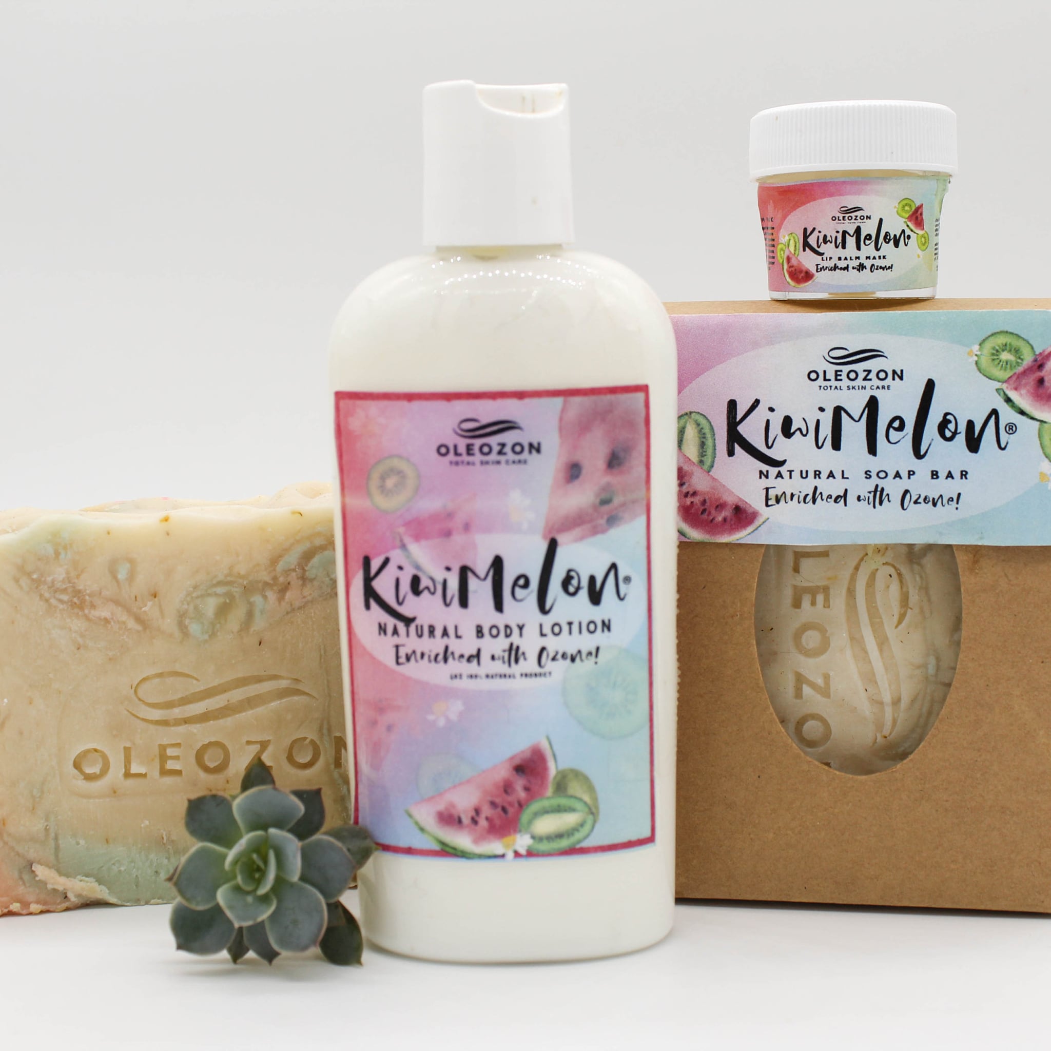 Body lotion bottle with white plastic, Kiwi Melon label, and fruit illustrations, next to soap bar and lip balm jar