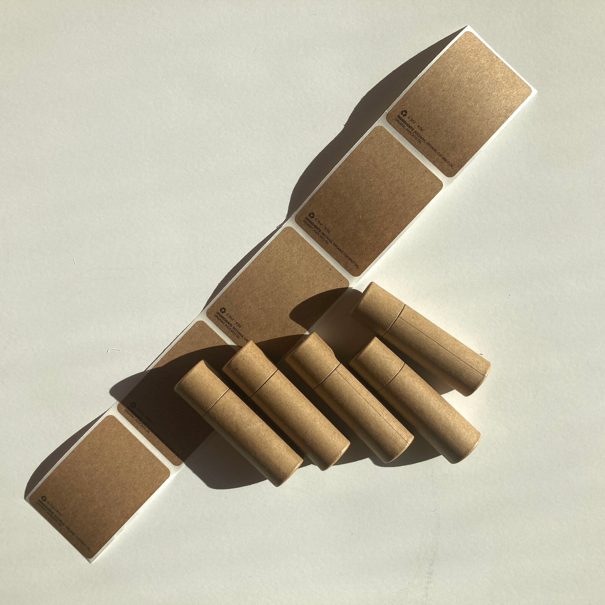 Kraft paper tubes with matching labels, brown and cylindrical, arranged on white surface