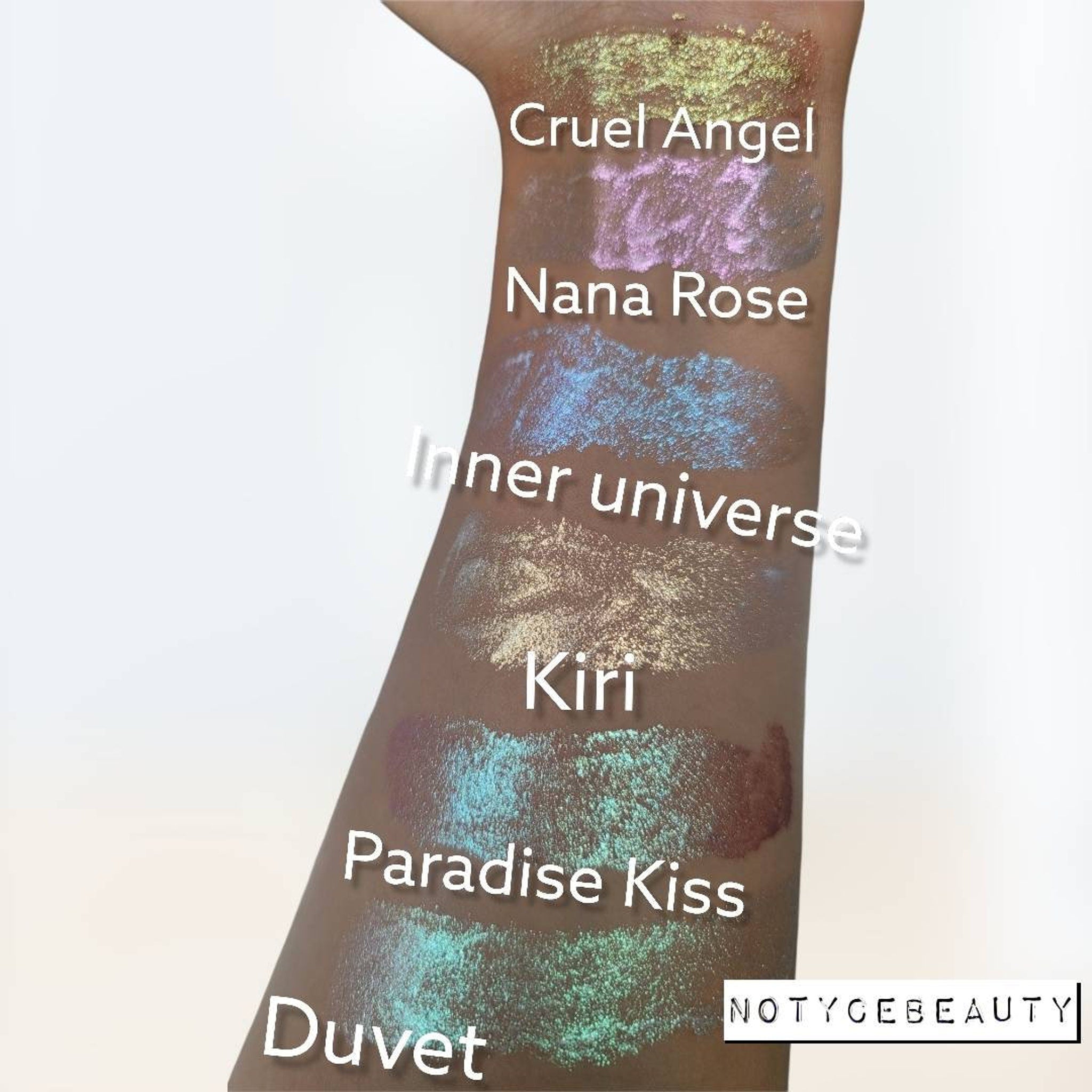 Close-up of three chameleon duochrome liquid eyeshadows in glass bottles with doe-foot applicators, showing shimmery violet, emerald, and bronze shades