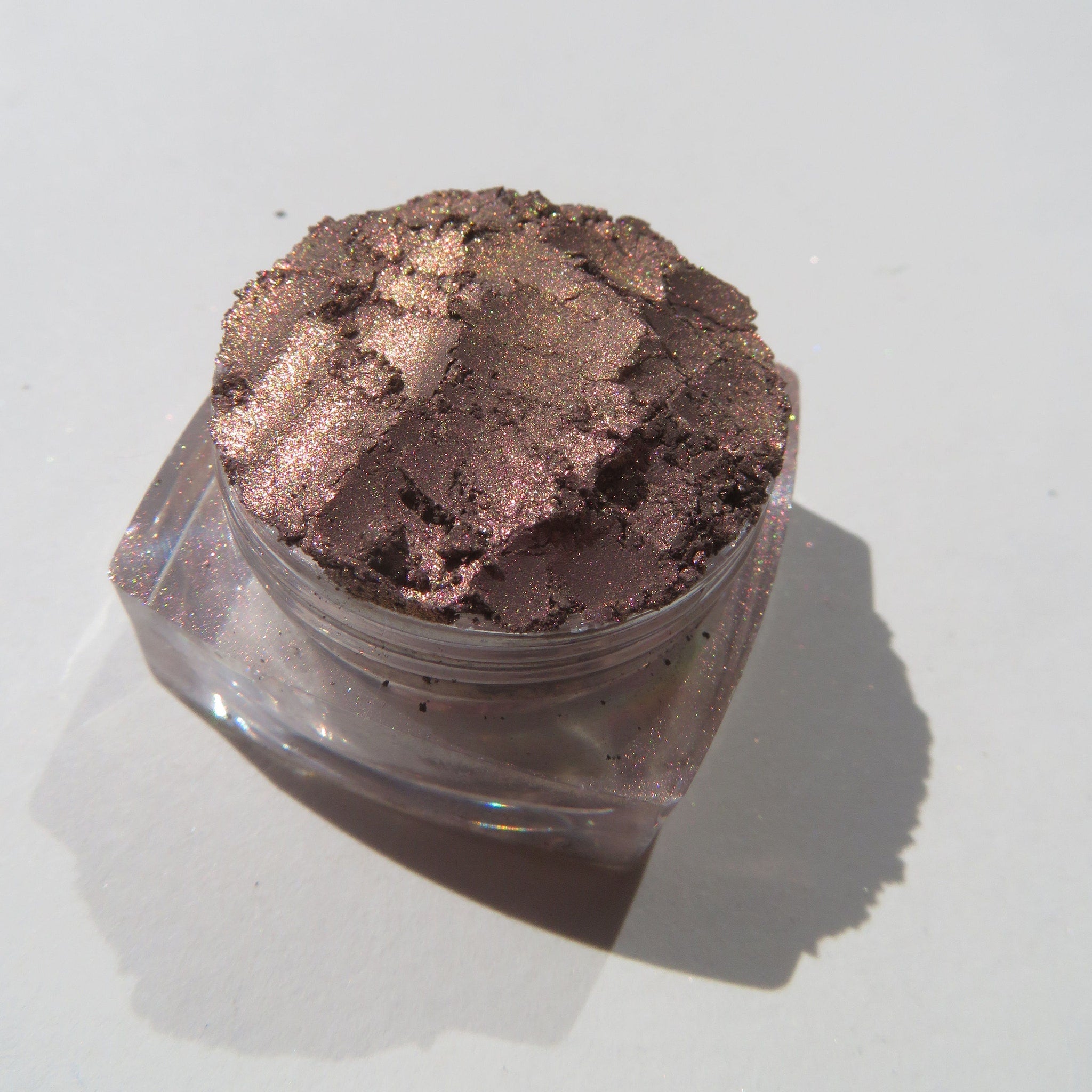 Side view of loose mineral eyeshadow in dark brown with shimmering rose metal finish, vegan and cruelty-free