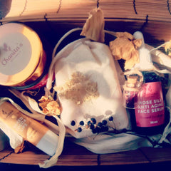 Skin care gift set with Chanita's Naturals products, wooden tray, white fabric, and dried flowers
