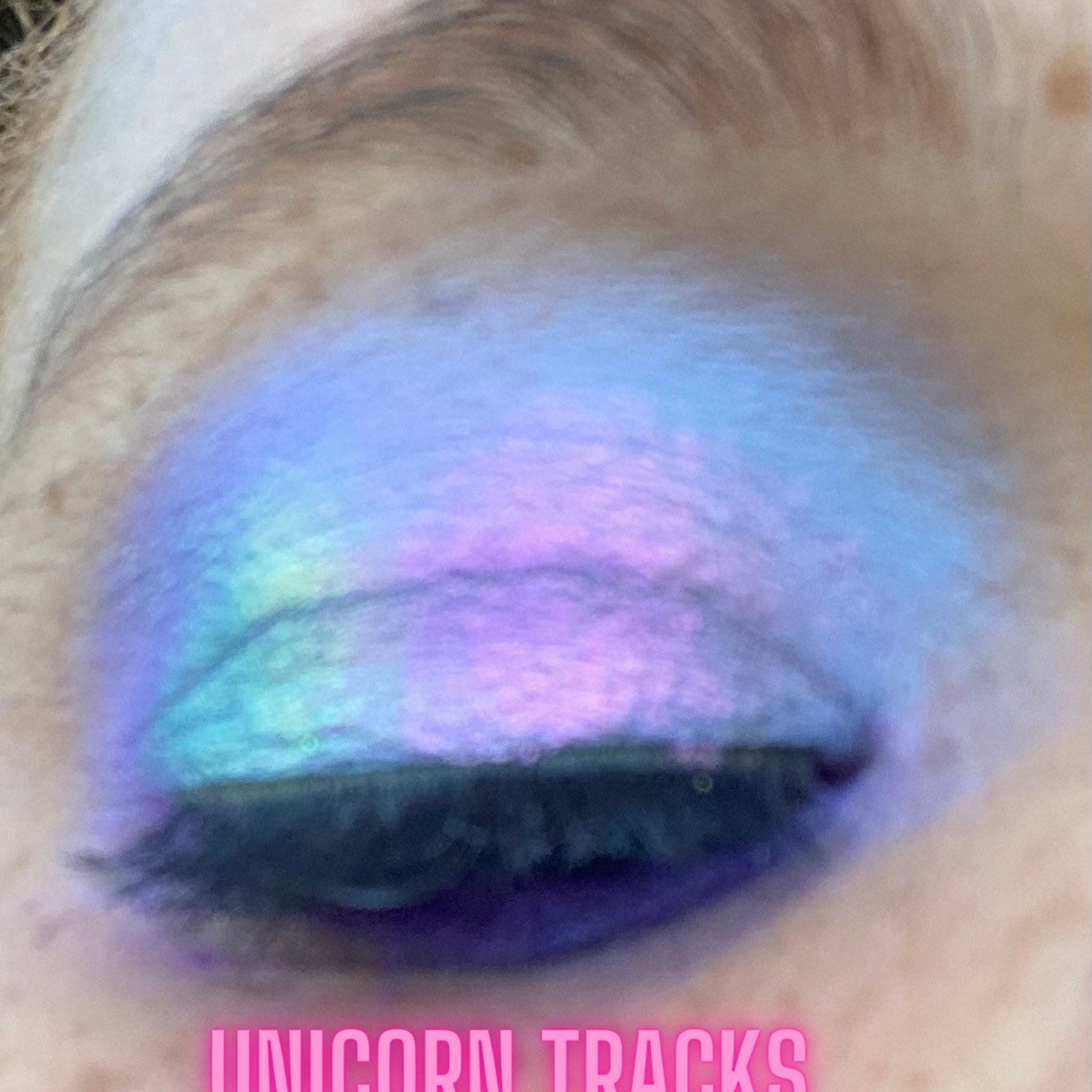 Close-up of multichrome unicorn tracks eyeshadow shifting colors under light in compact palette