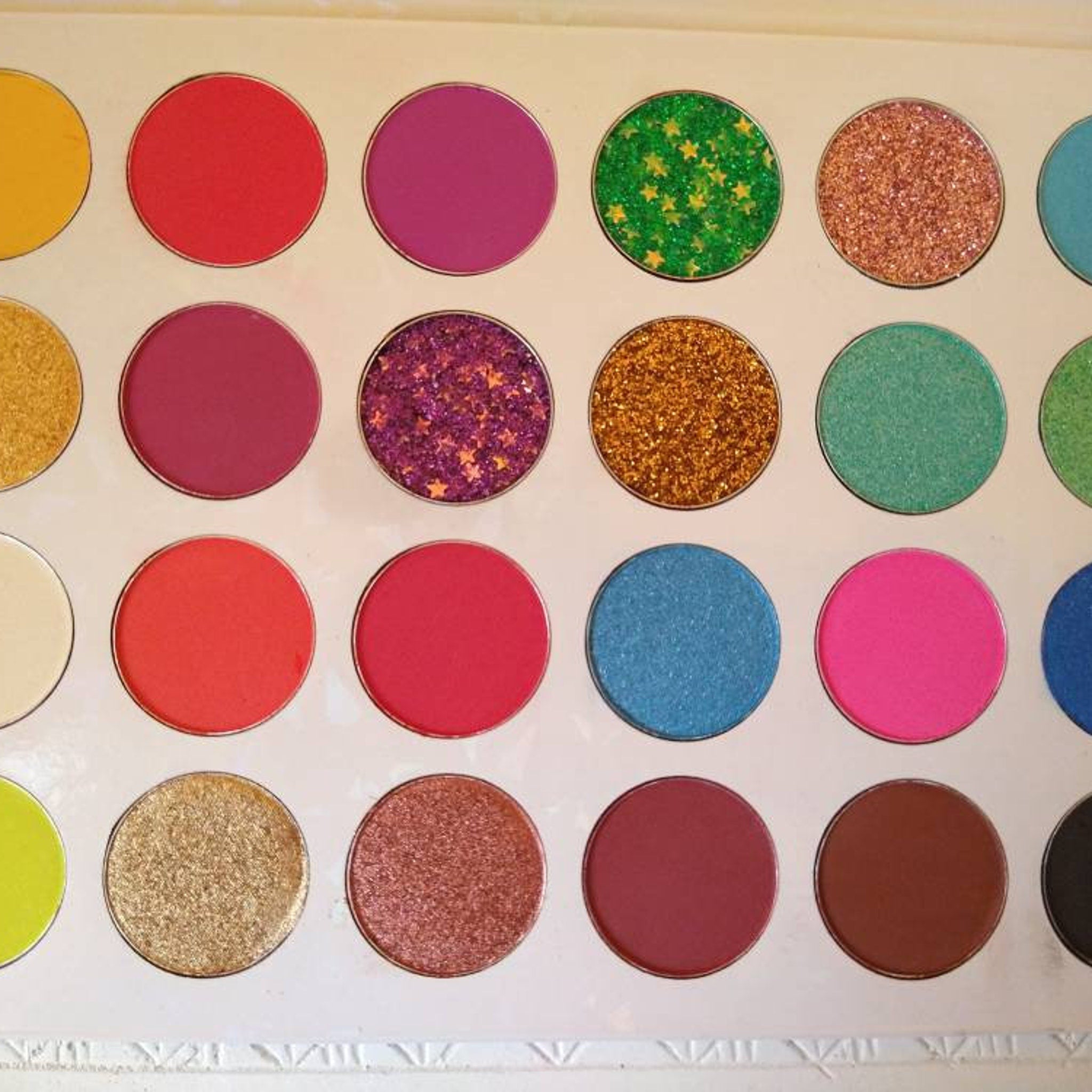Eyeshadow palette with various colors and textures including glitter and matte finishes
