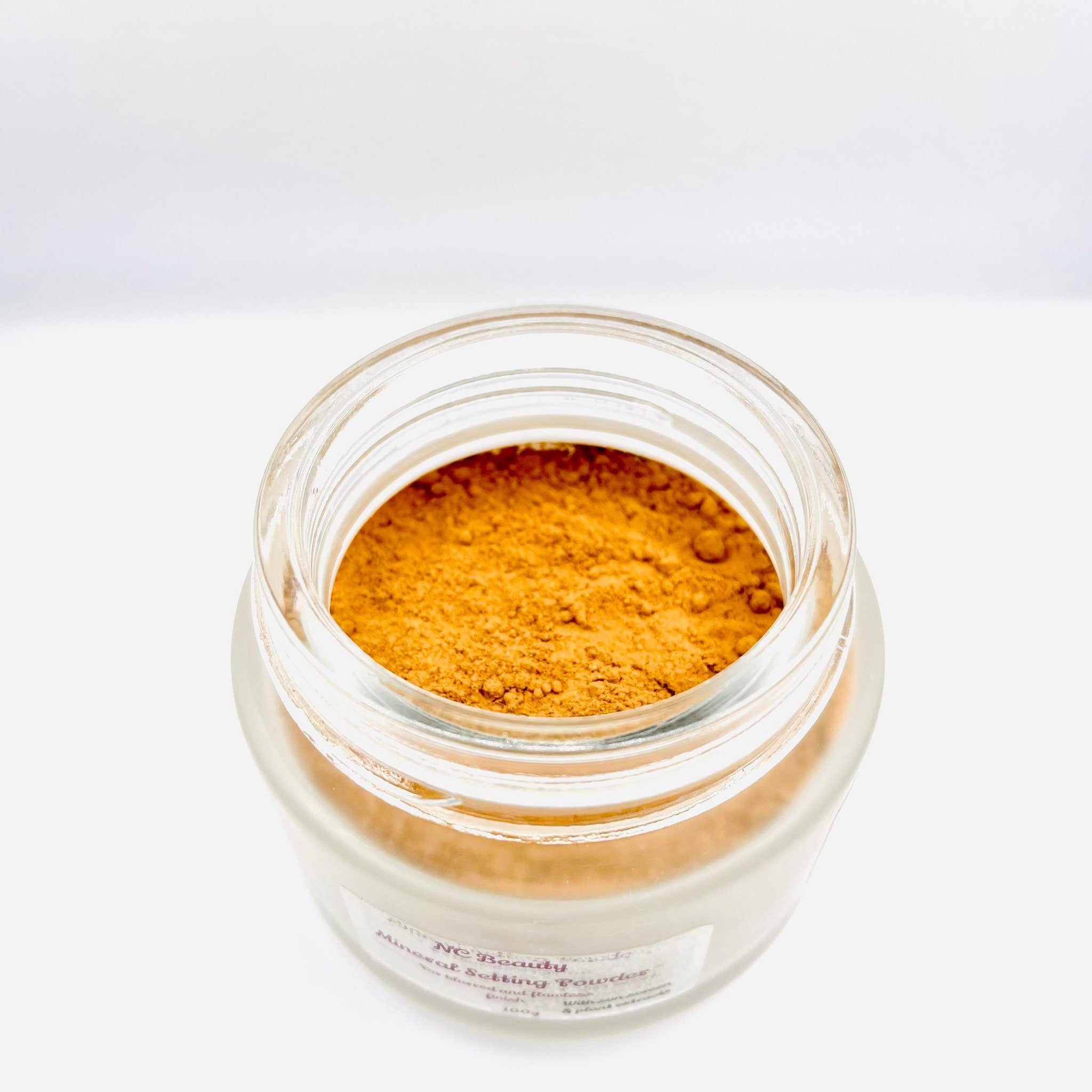 Mineral setting powder in jar, clear glass jar with orange powder, NC Beauty label