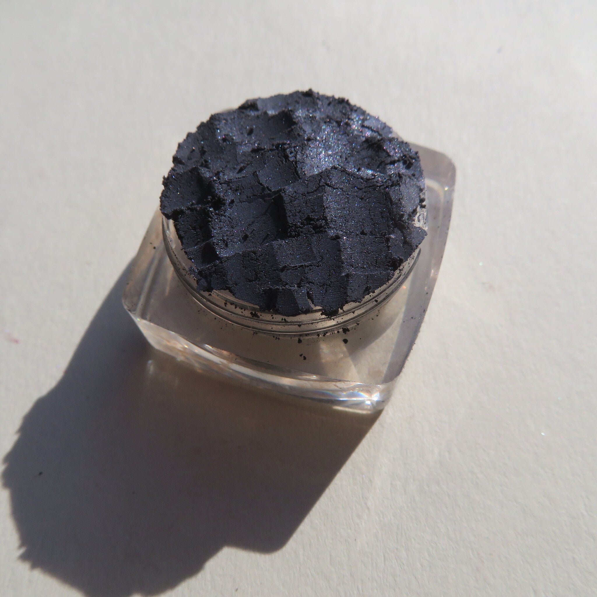 Close-up of navy blue loose powder eyeshadow with shimmer particles, showcasing fine mineral texture
