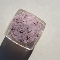 Hand applying muted pale purple matte mineral eyeshadow with brush onto eyelid