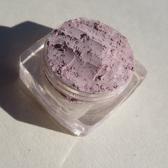 Side view of loose mineral eyeshadow in muted pale purple matte finish, showcasing fine powder texture
