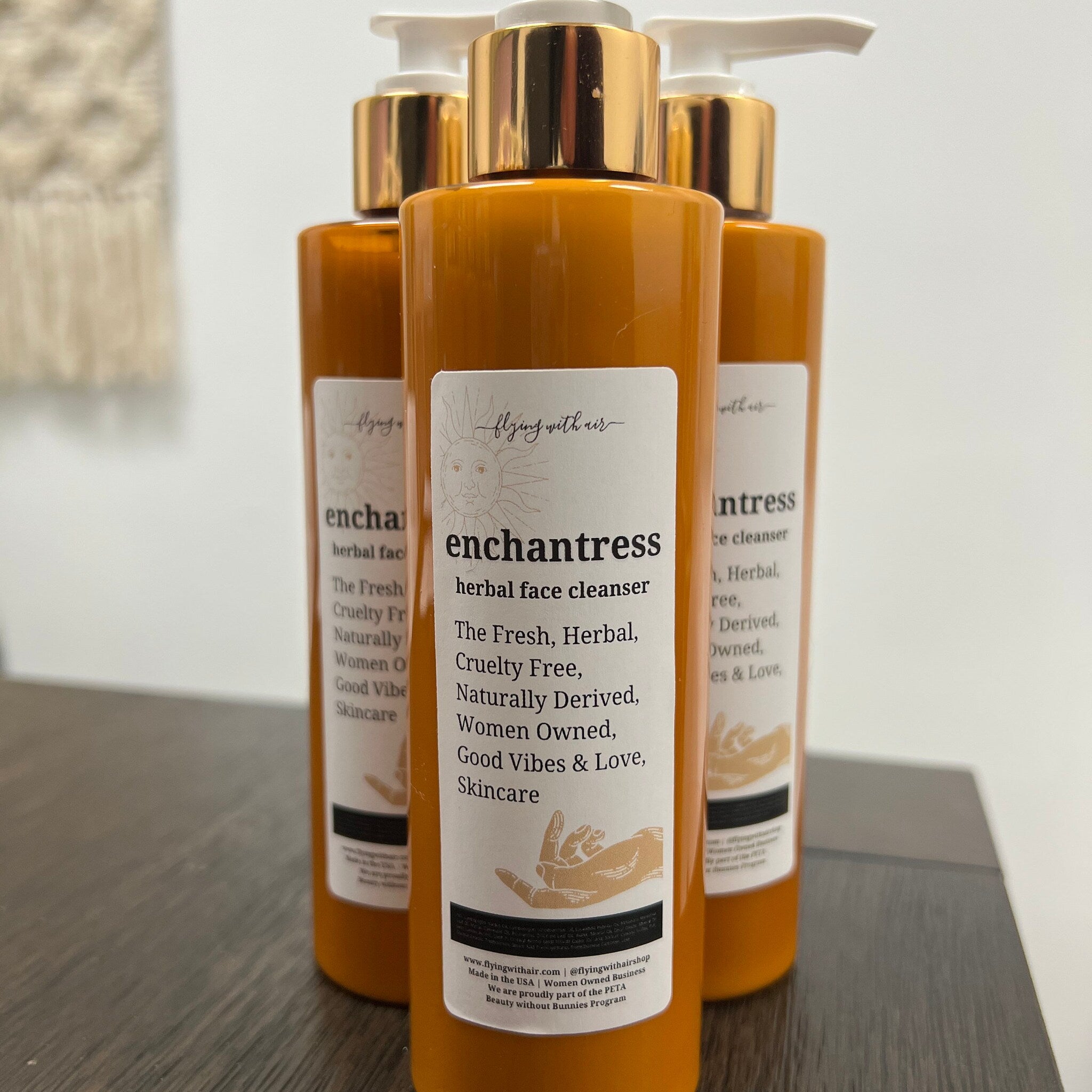 Face cleanser bottles, orange glass, gold pump tops, white label with text and logo