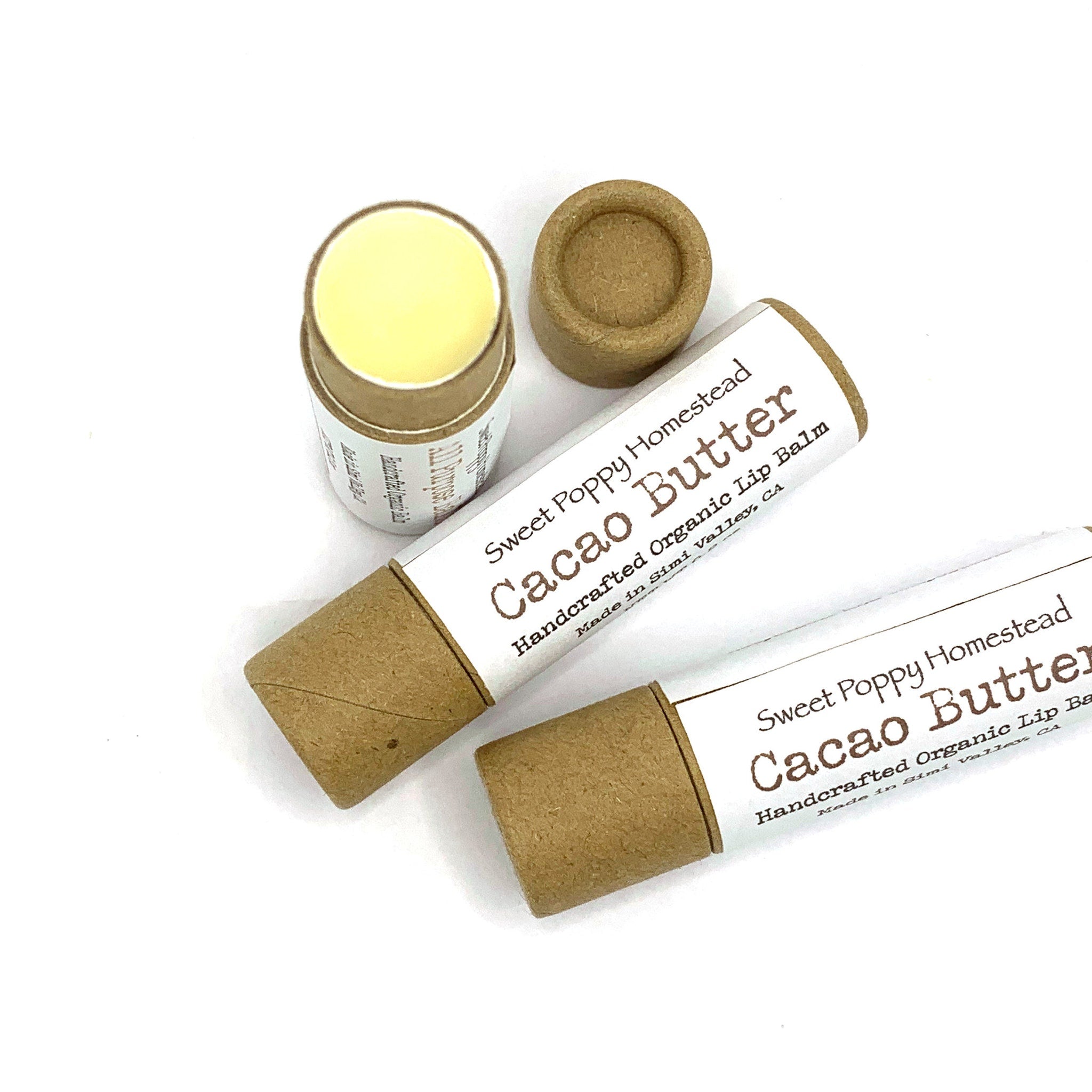 Lip balm tubes in brown cardboard, white label, and yellow balm visible, Sweet Poppy Homestead brand