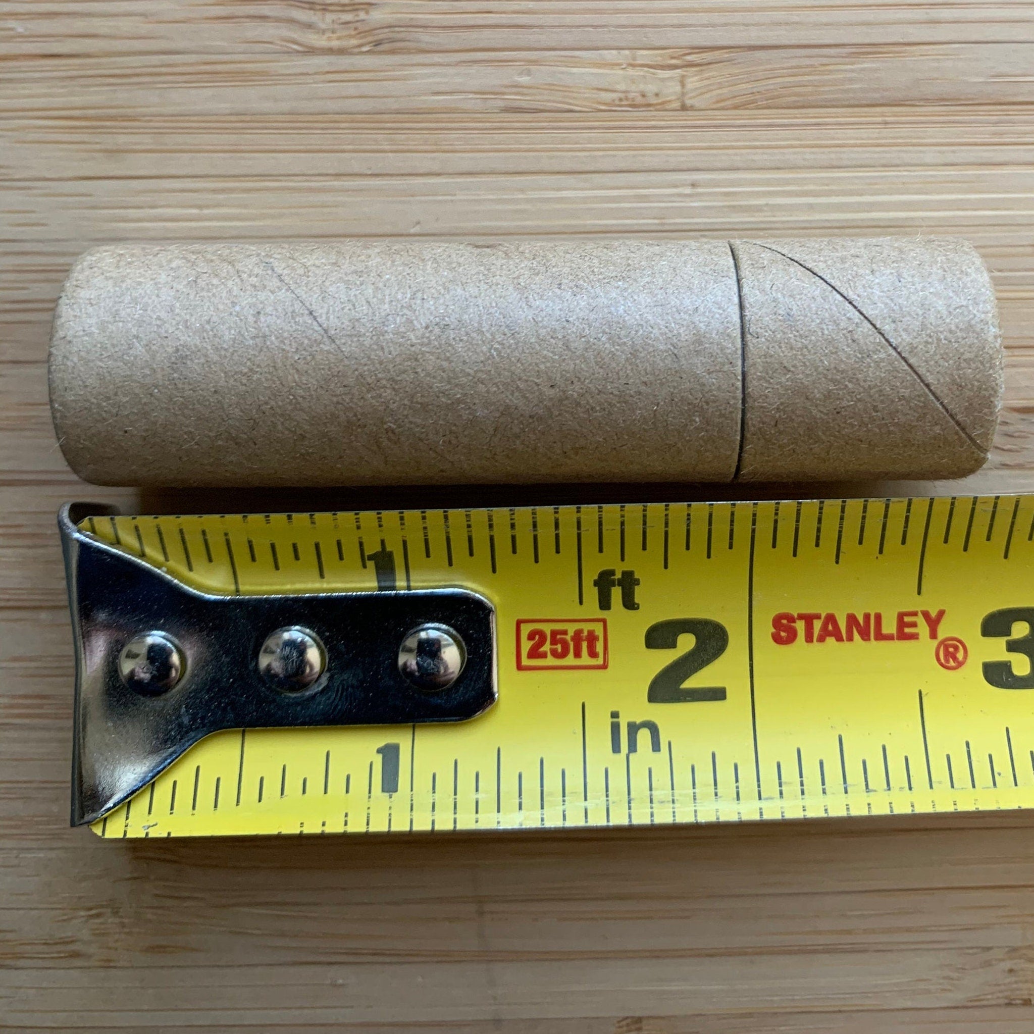Measuring tape with yellow and black markings next to a brown cardboard tube