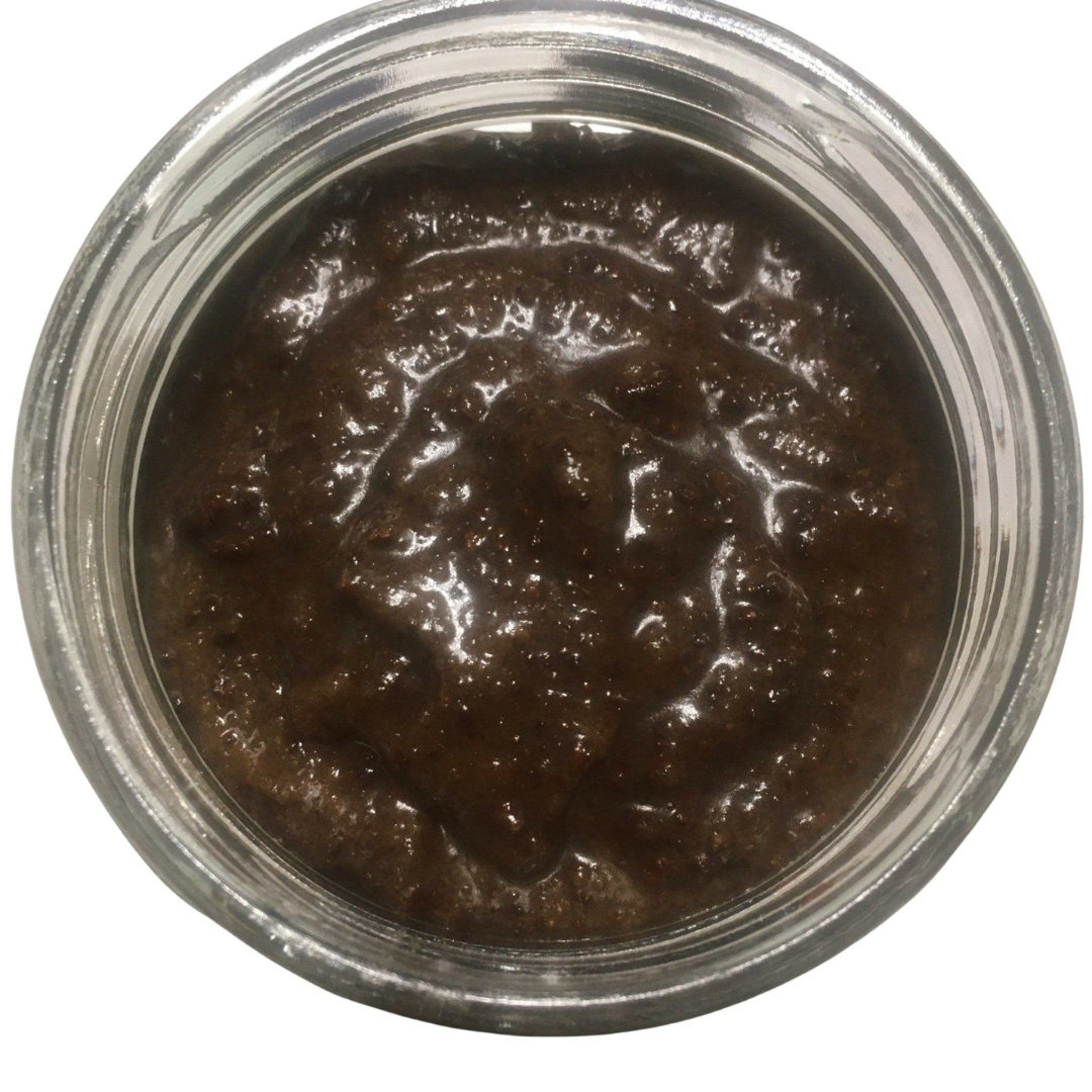 Brown paste in a clear glass jar with a glossy, textured surface and a reflective glass rim