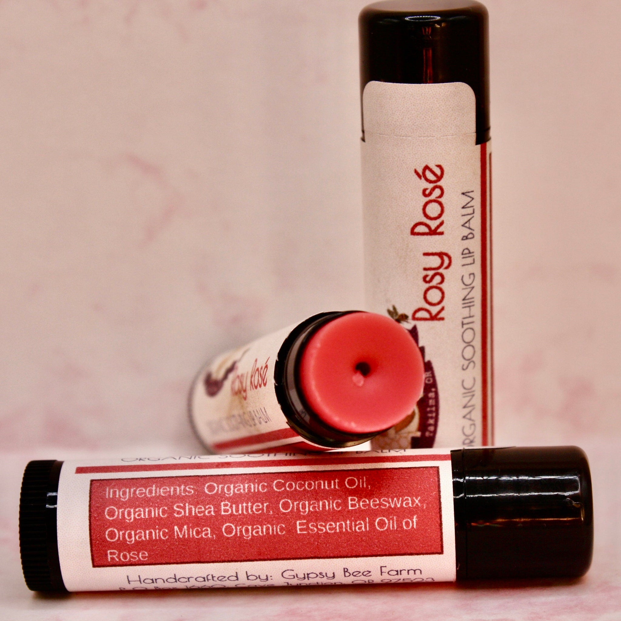 Lip balm tubes with pink balm, black caps, and "Rosy Rosé" label text