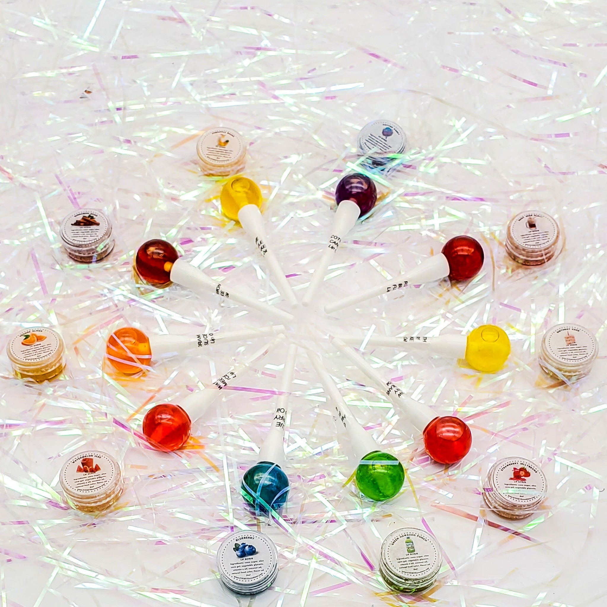Lollipops with colorful round candy, white sticks, and small round containers on iridescent paper background