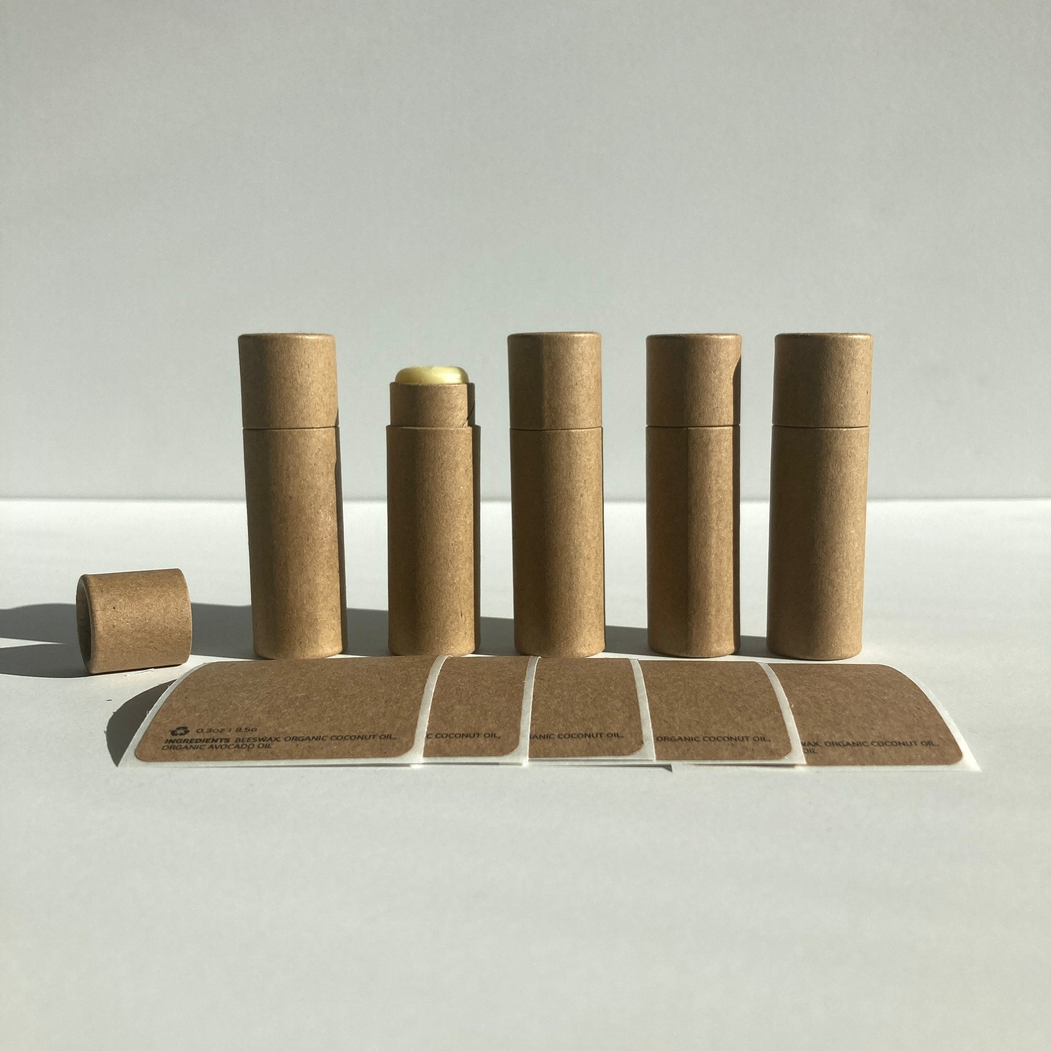 Lip balm tubes, brown cardboard material, with labels and exposed balm, natural style