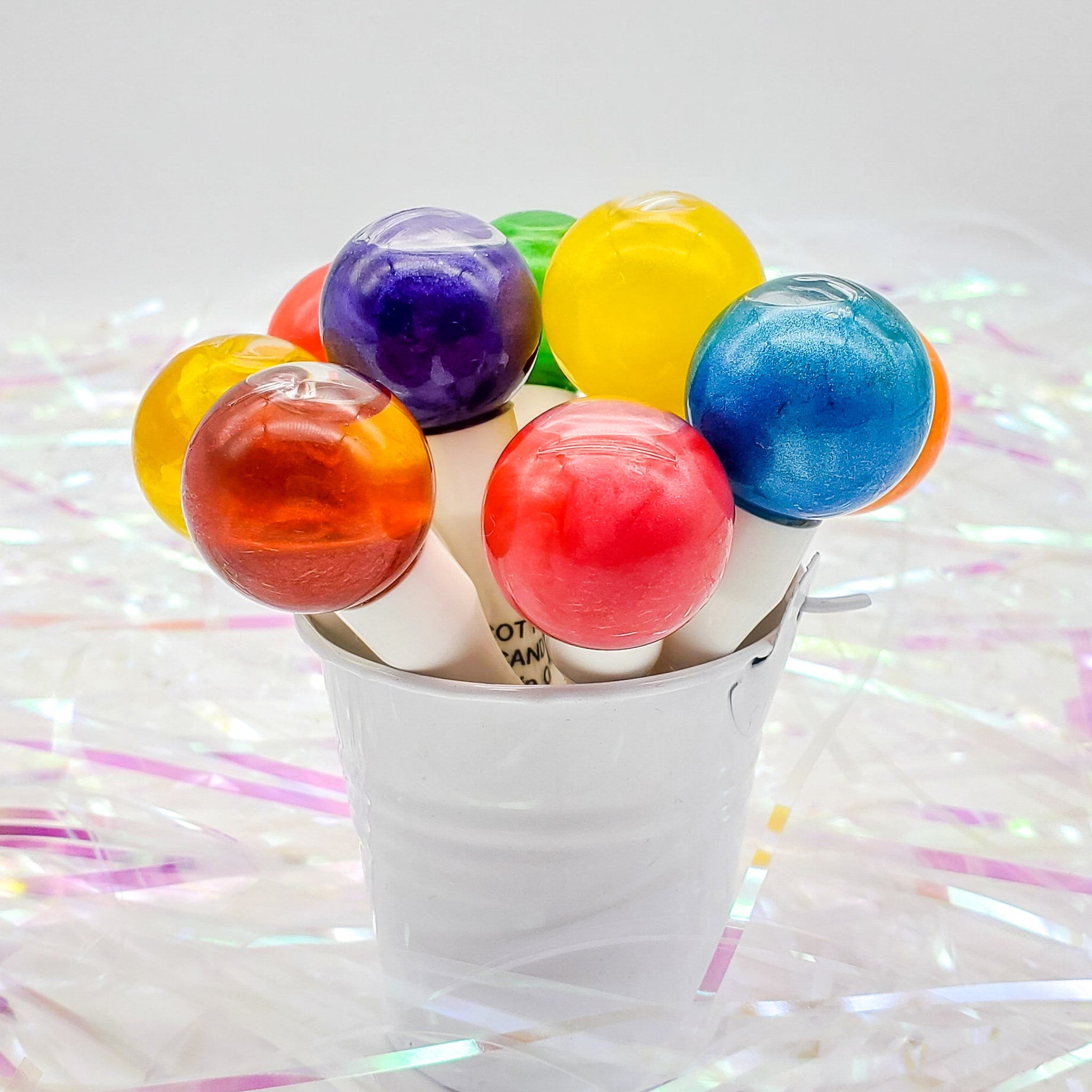 Colorful lollipops in a white bucket, various colors, shiny, on a white background