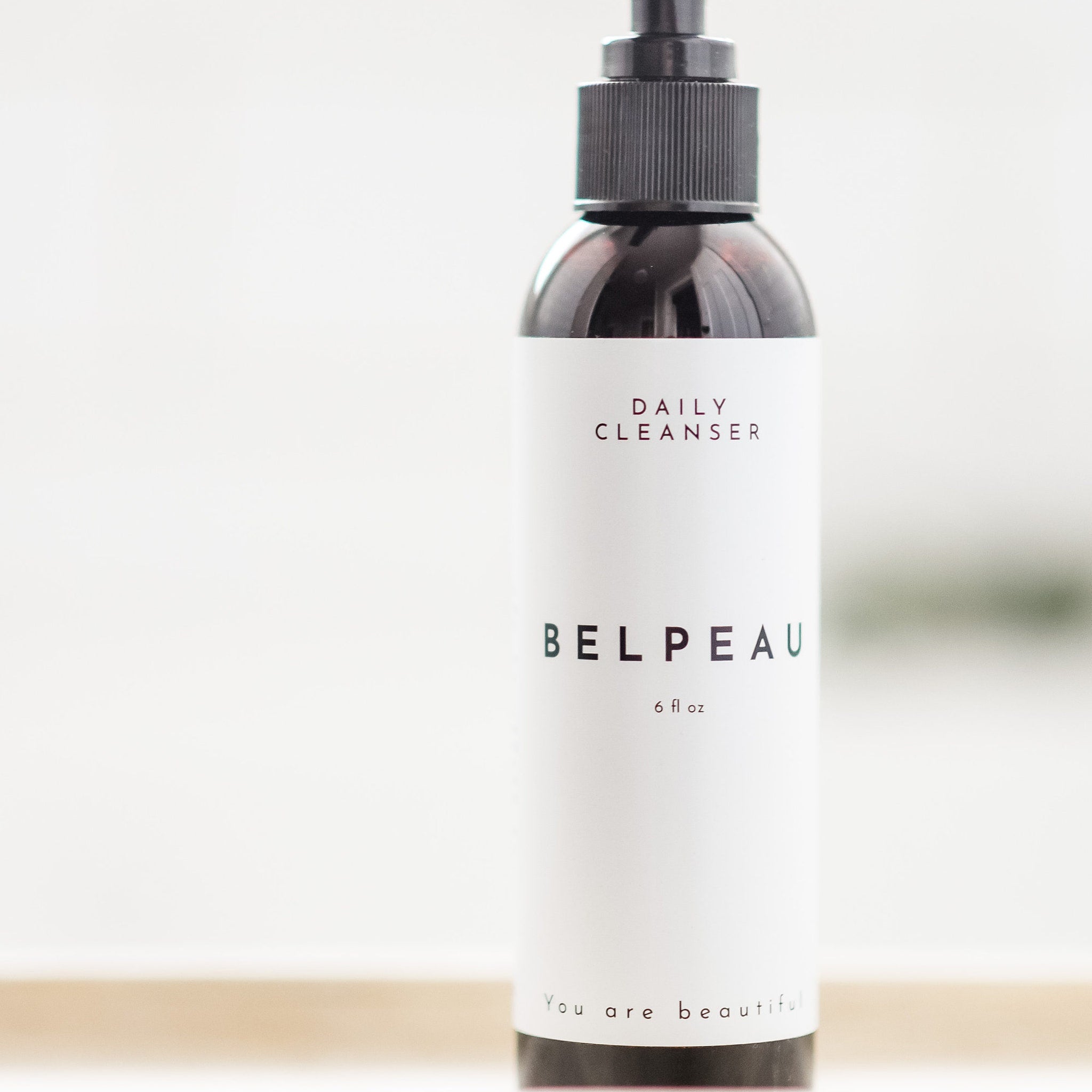 Daily cleanser bottle with black pump and white label, "BELPEAU" text visible