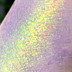 Eye shadow swatch with lavender and iridescent foil pigment, showing texture and color