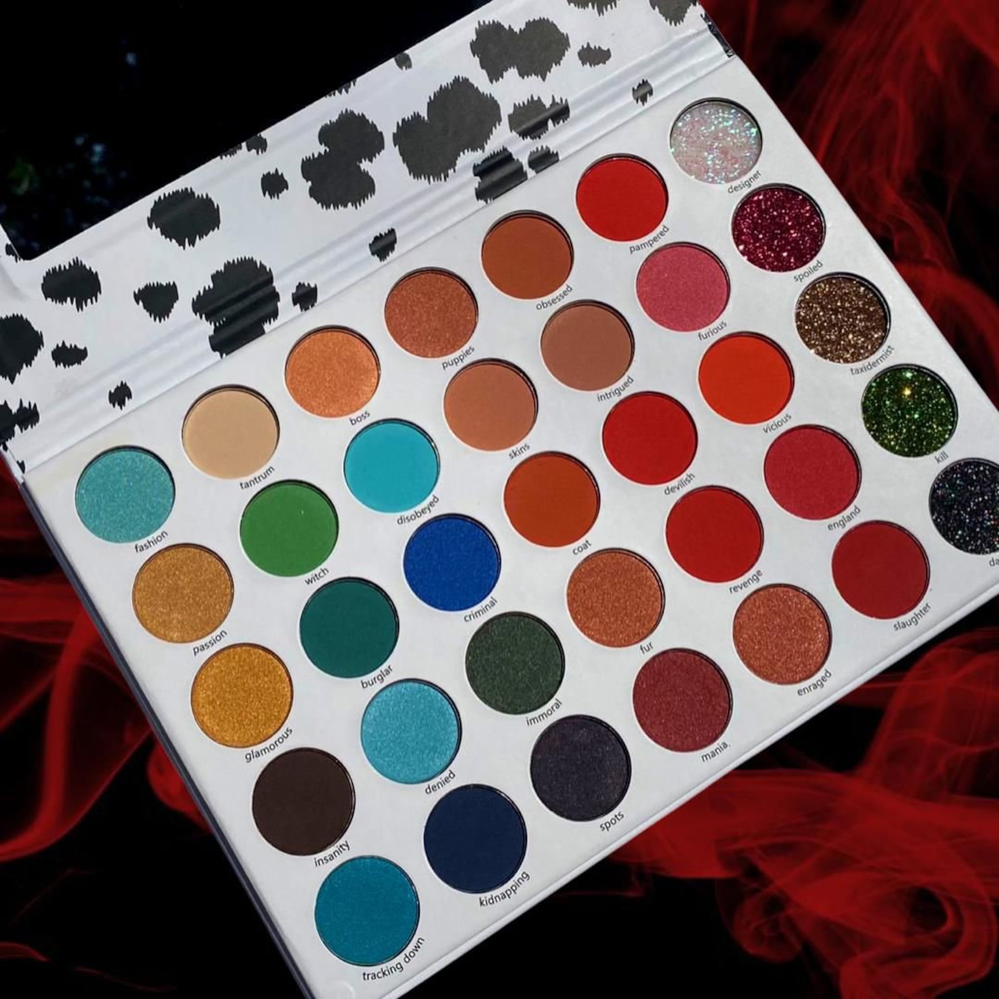 Eyeshadow palette with multiple colors, glitter, and white dalmatian print packaging