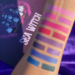 Eyeshadow swatches in various colors on arm, with "SEA WITCH" text visible on background design.