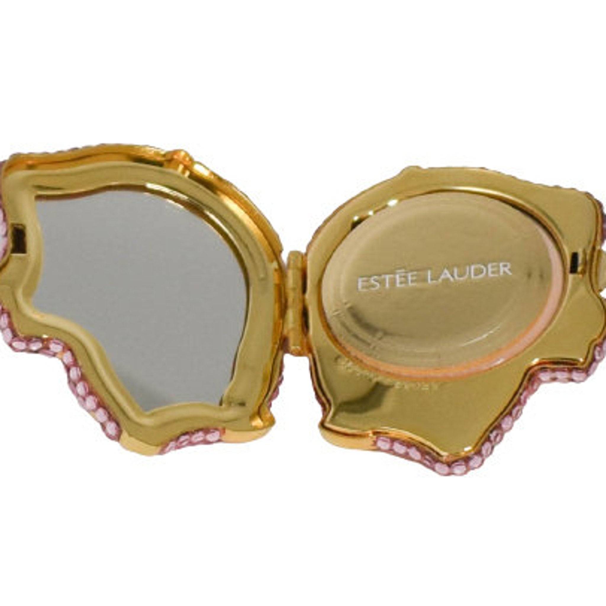 Compact mirror with gold frame, pink gem accents, and Estee Lauder text visible