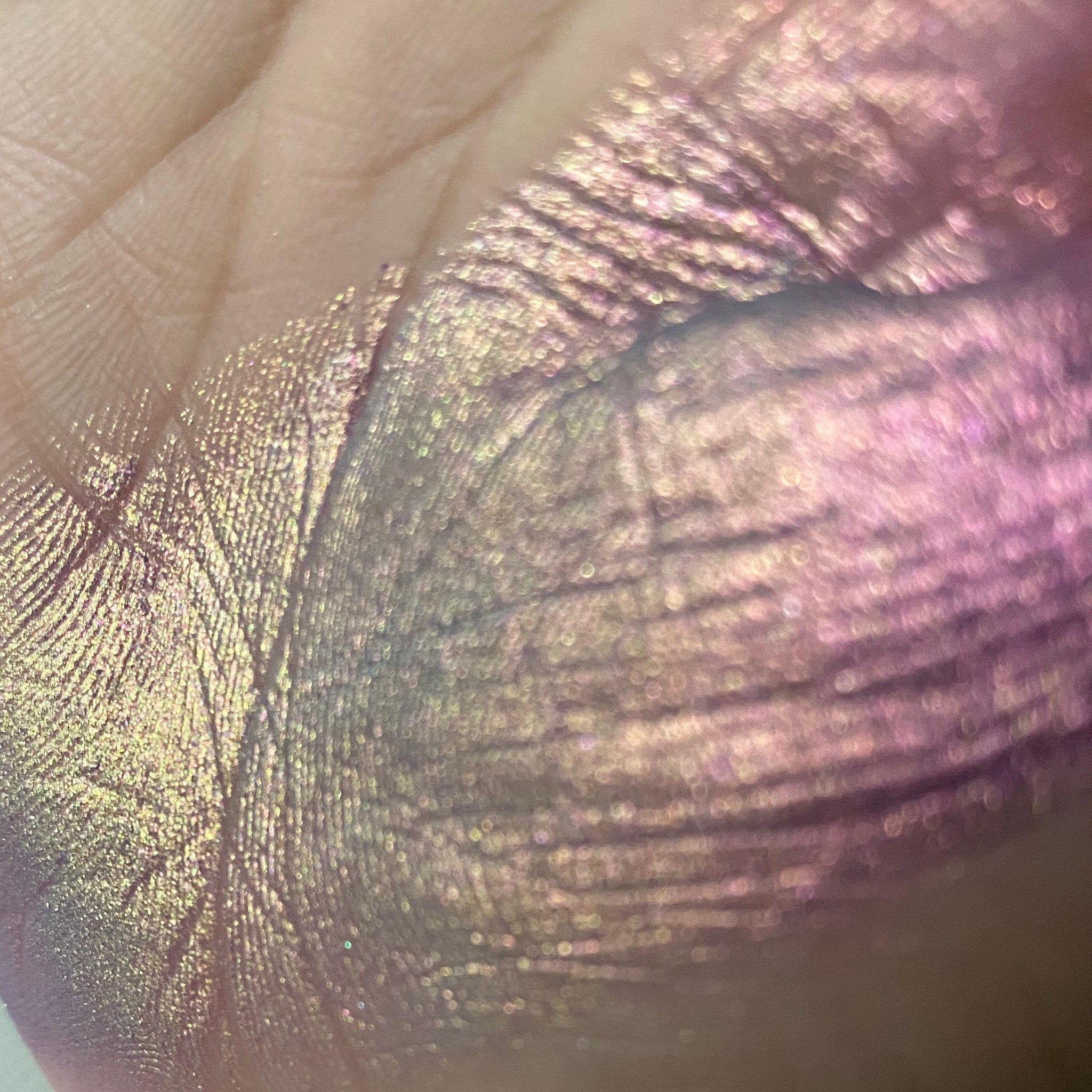 Side view of multichrome eyeshadow palette showing shifting iridescent hues in compact case