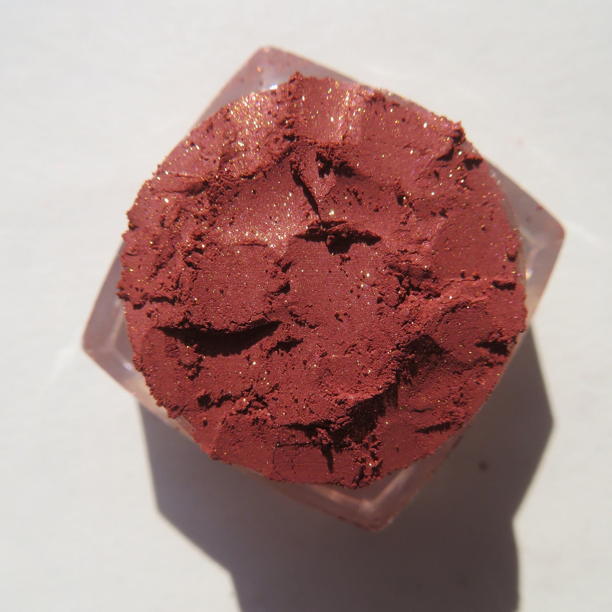 Side view of brick red orange shimmer loose mineral eyeshadow with eco-friendly packaging catching light