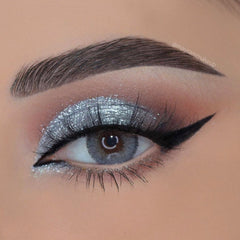 Side view of platinum eye shadow palette showcasing shimmering silver and charcoal shades in sleek mirrored compact