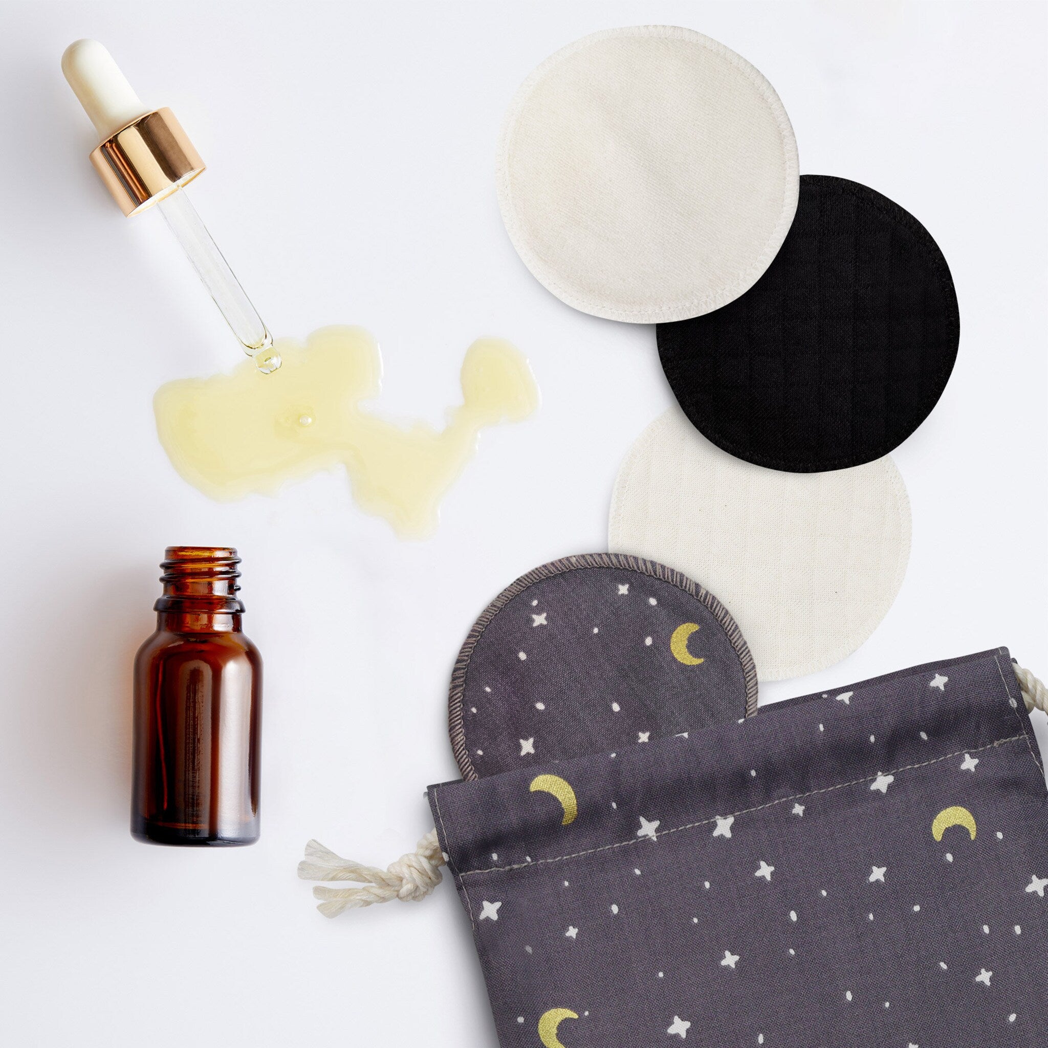 Reusable facial rounds in black, white, and patterned fabric with drawstring bag and oil bottle