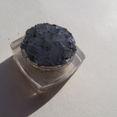 Hand applying navy blue shimmer loose powder eyeshadow with a fluffy brush for a smoky eye look