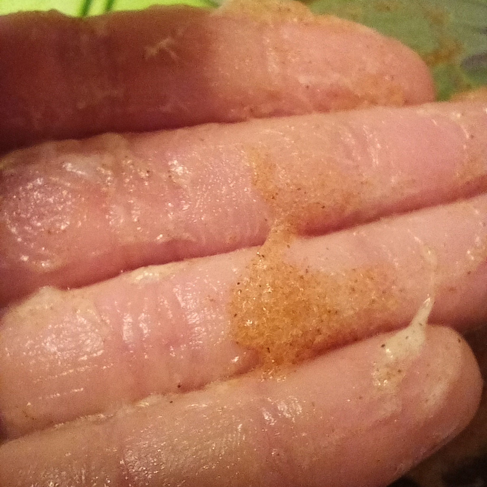 Pink fingers with brown speckles, close-up view of hand.