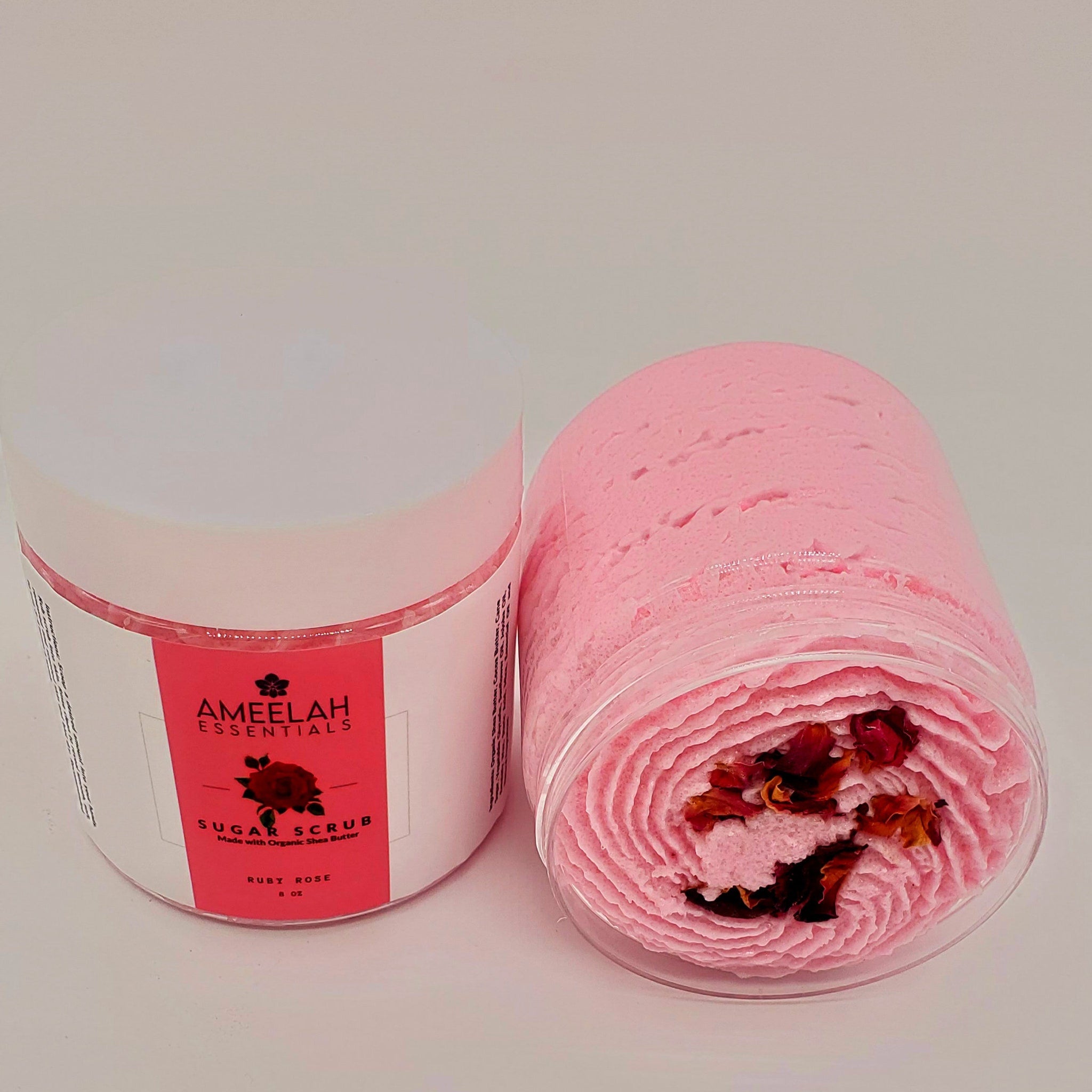 Sugar scrub in clear container with pink swirl, dried rose petals, Ameelah Essentials label