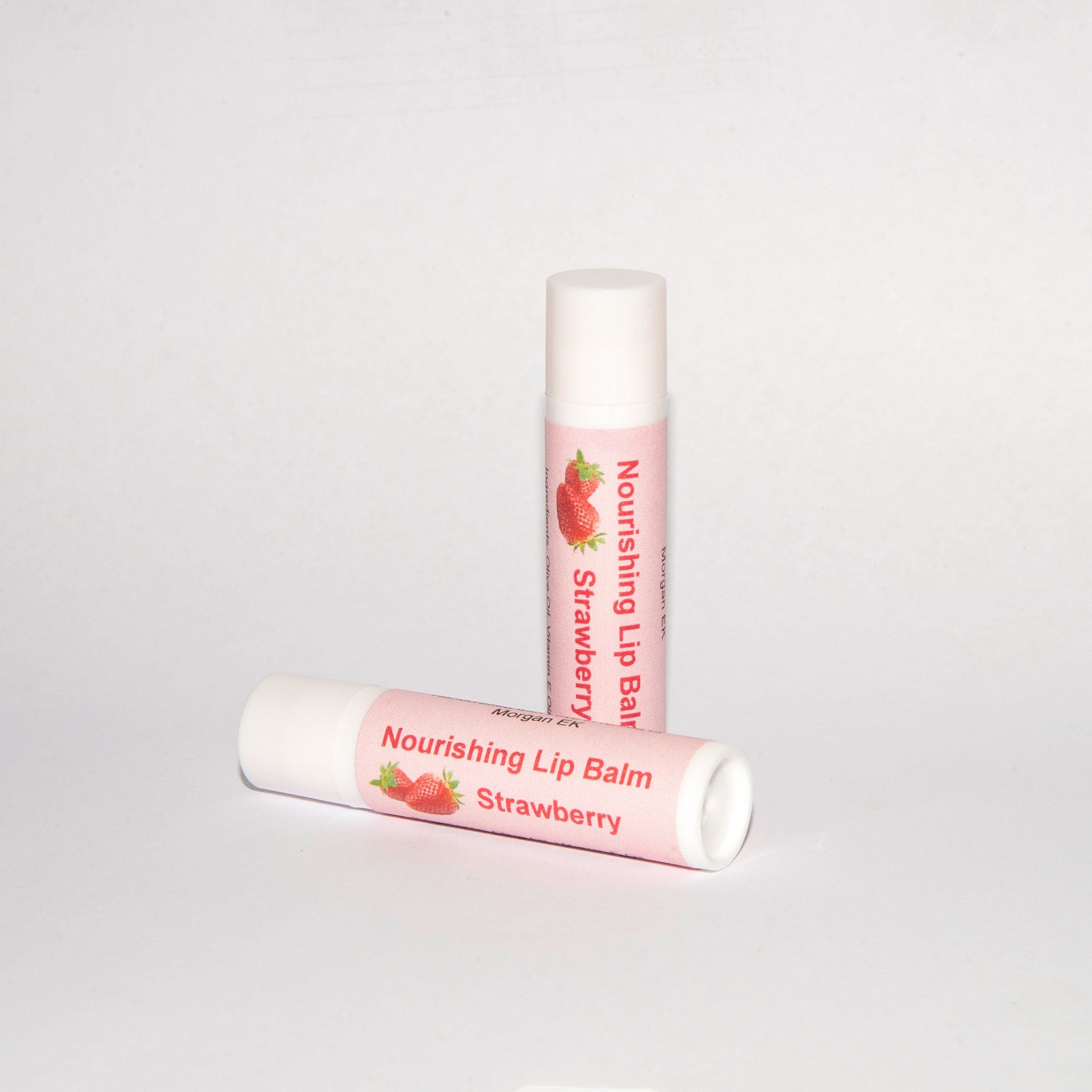 Lip balm tubes with white and pink labels, strawberry illustration, Morgan EK text visible