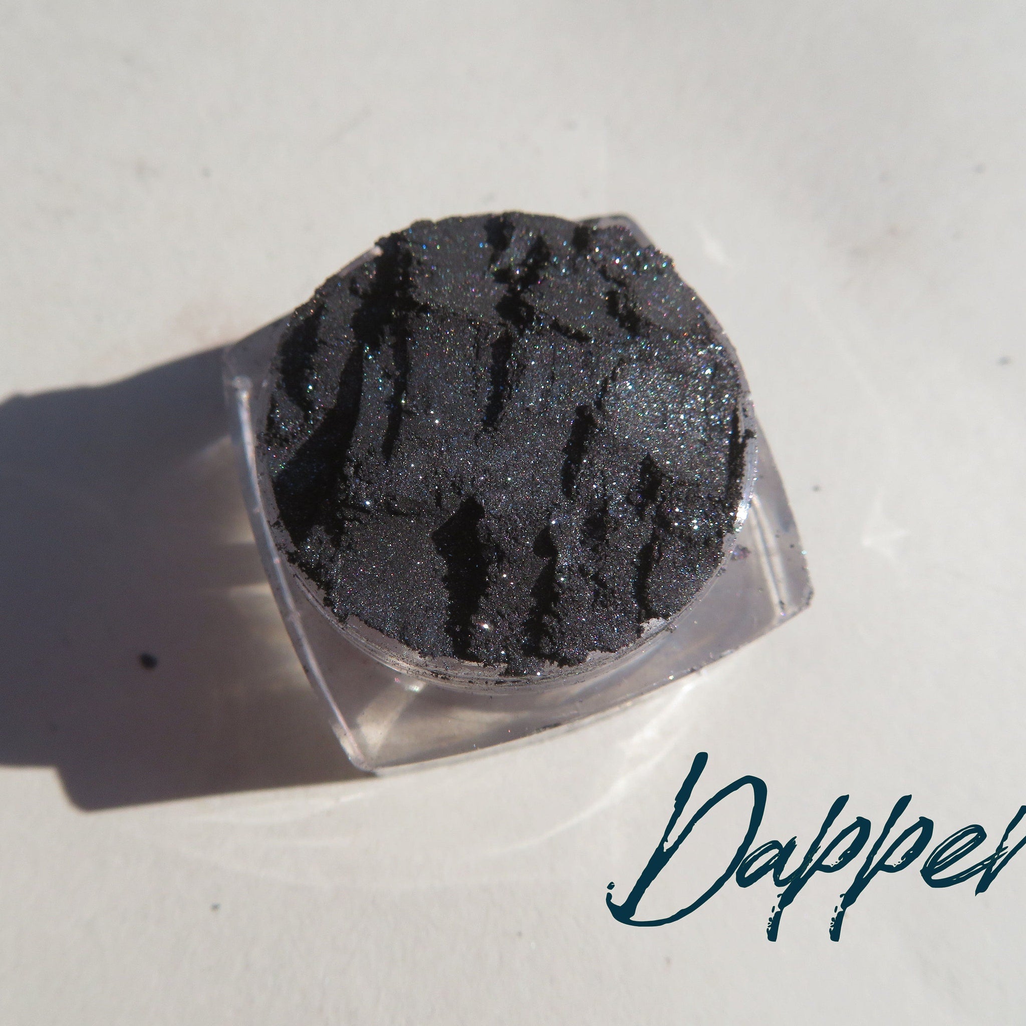 Side view of black silver shimmer loose mineral eyeshadow in a sleek round jar with vegan label