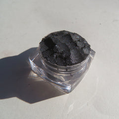 Hand applying black silver shimmer vegan mineral eyeshadow with fingertip for a smoky eye look
