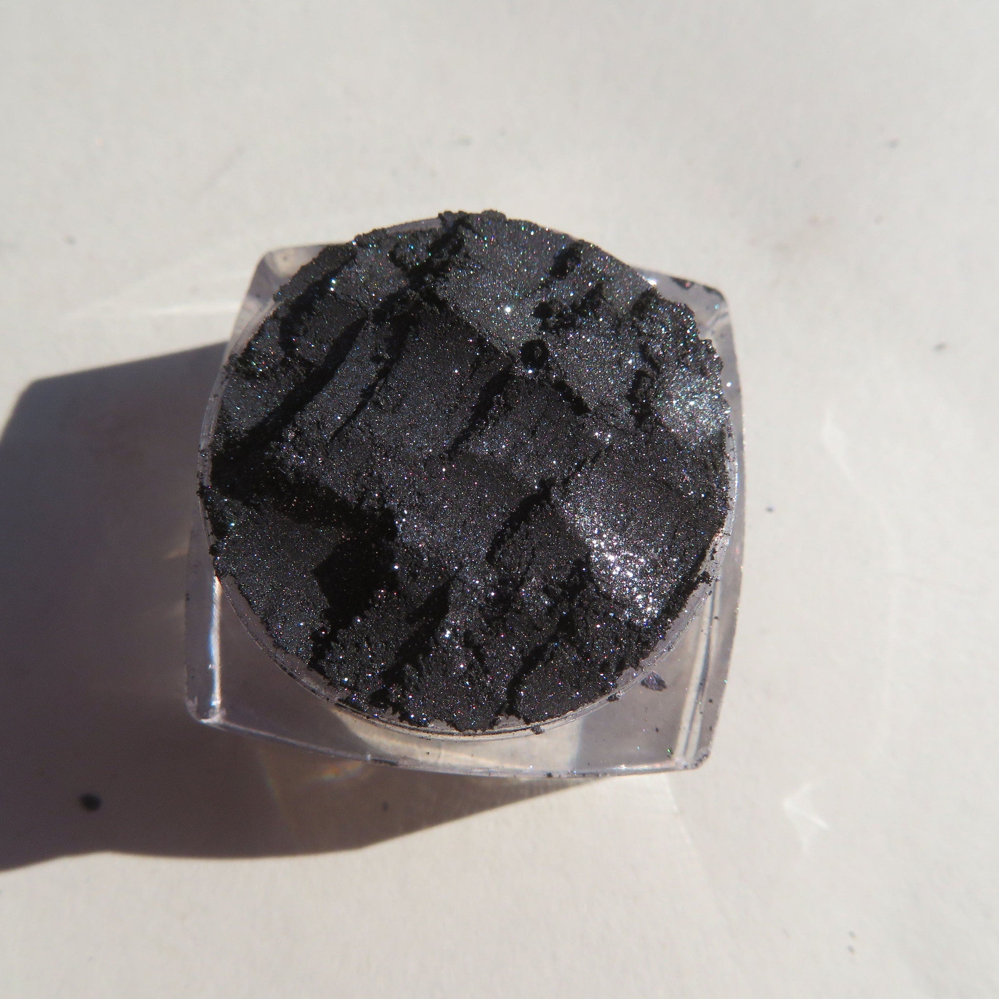 Black silver shimmer loose mineral eyeshadow in clear jar with gold lid, vegan and cruelty-free label visible