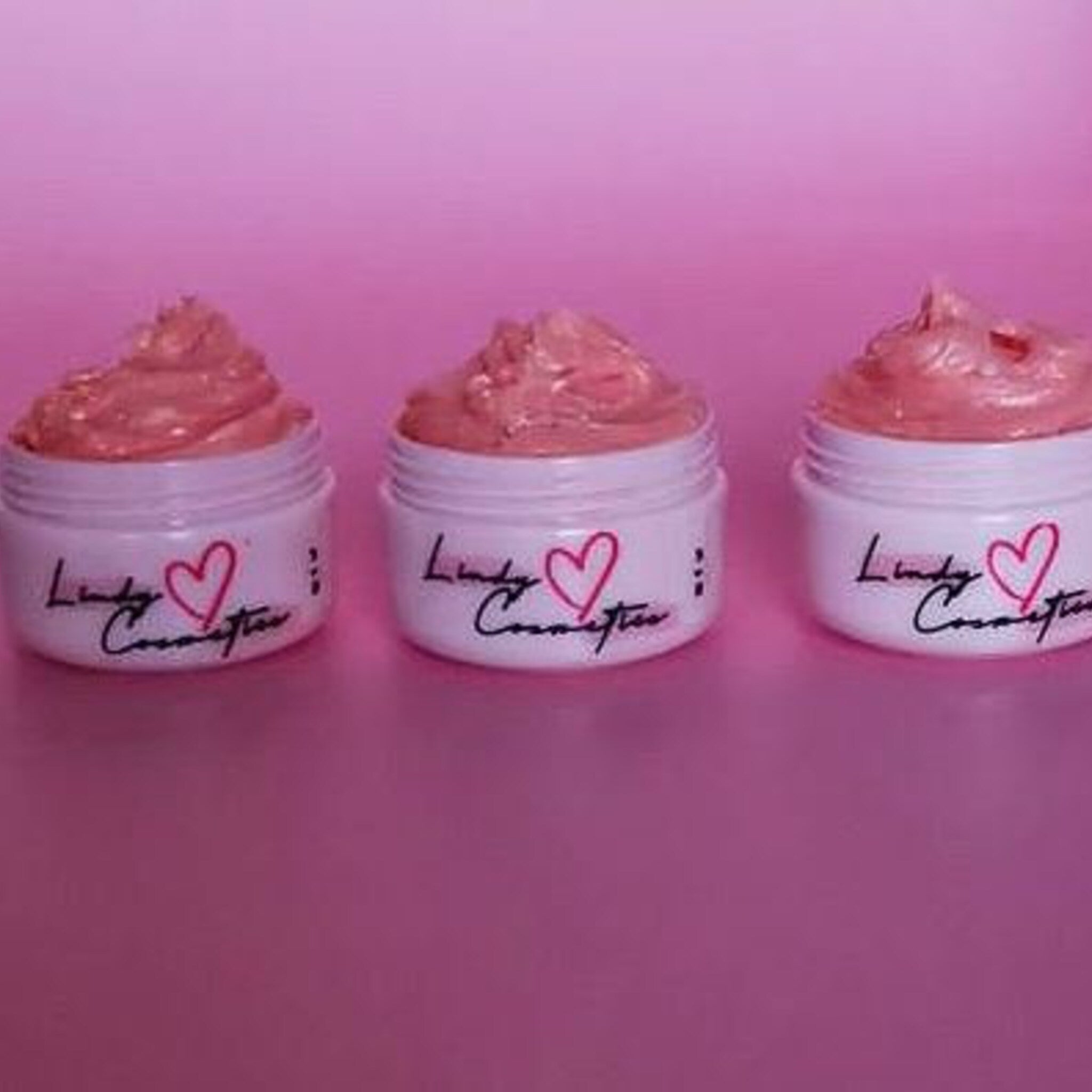 Cosmetic jars with pink cream, white jars, and Lindy Cosmetics logo, on pink background