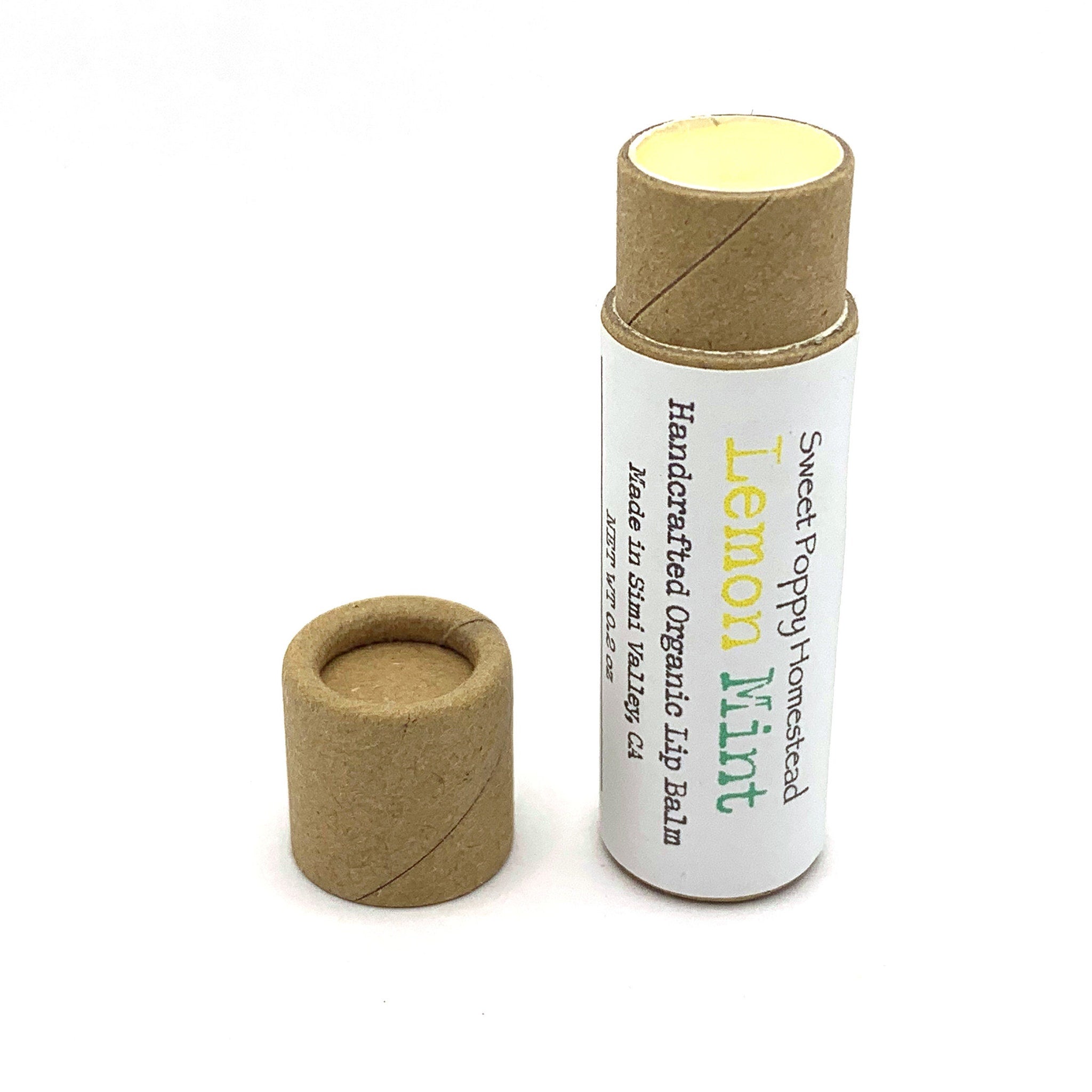 Lip balm tube with brown cardboard, white label, and yellow balm inside, Sweet Poppy Homestead brand