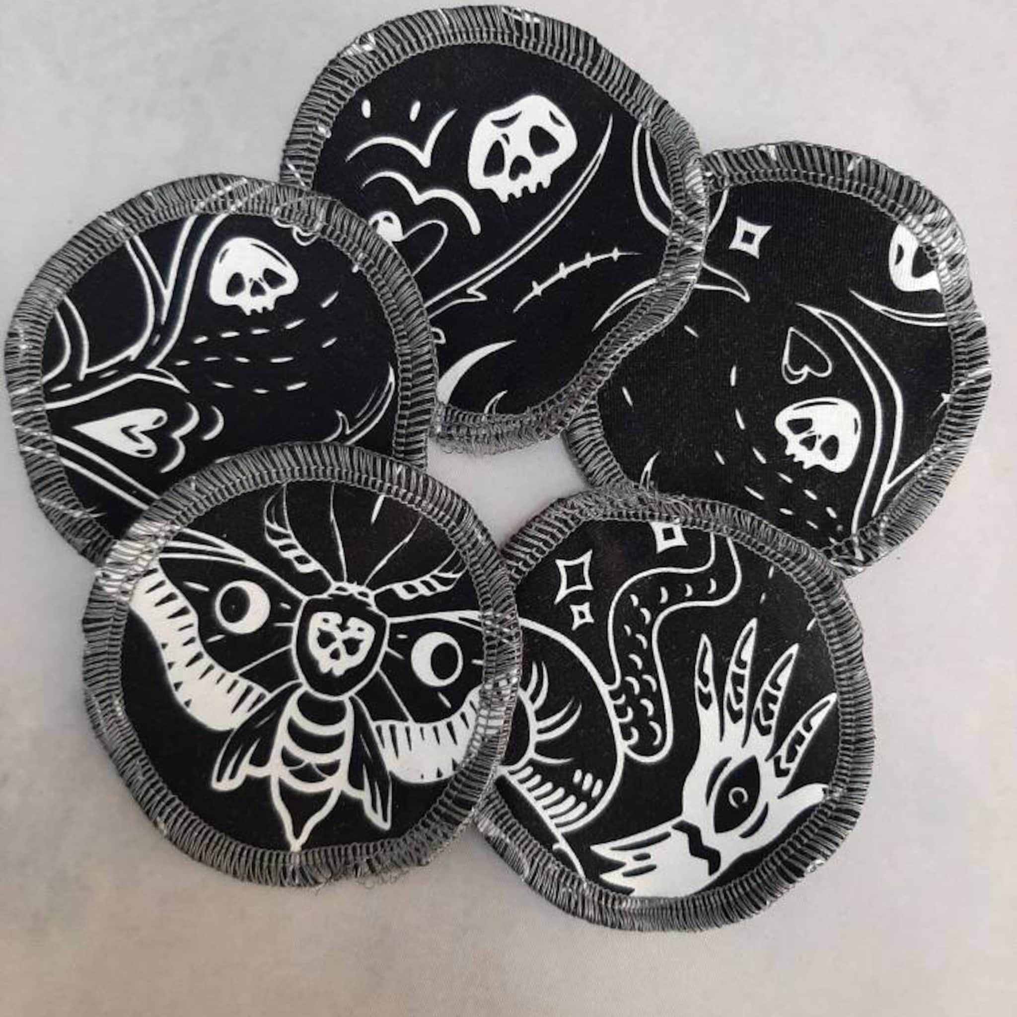 Reusable facial rounds with black and white skull and moth patterns, gray stitched edges