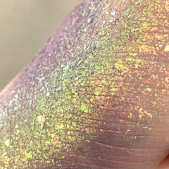 Glitter flakes with green, yellow, and purple iridescence on skin, close-up view